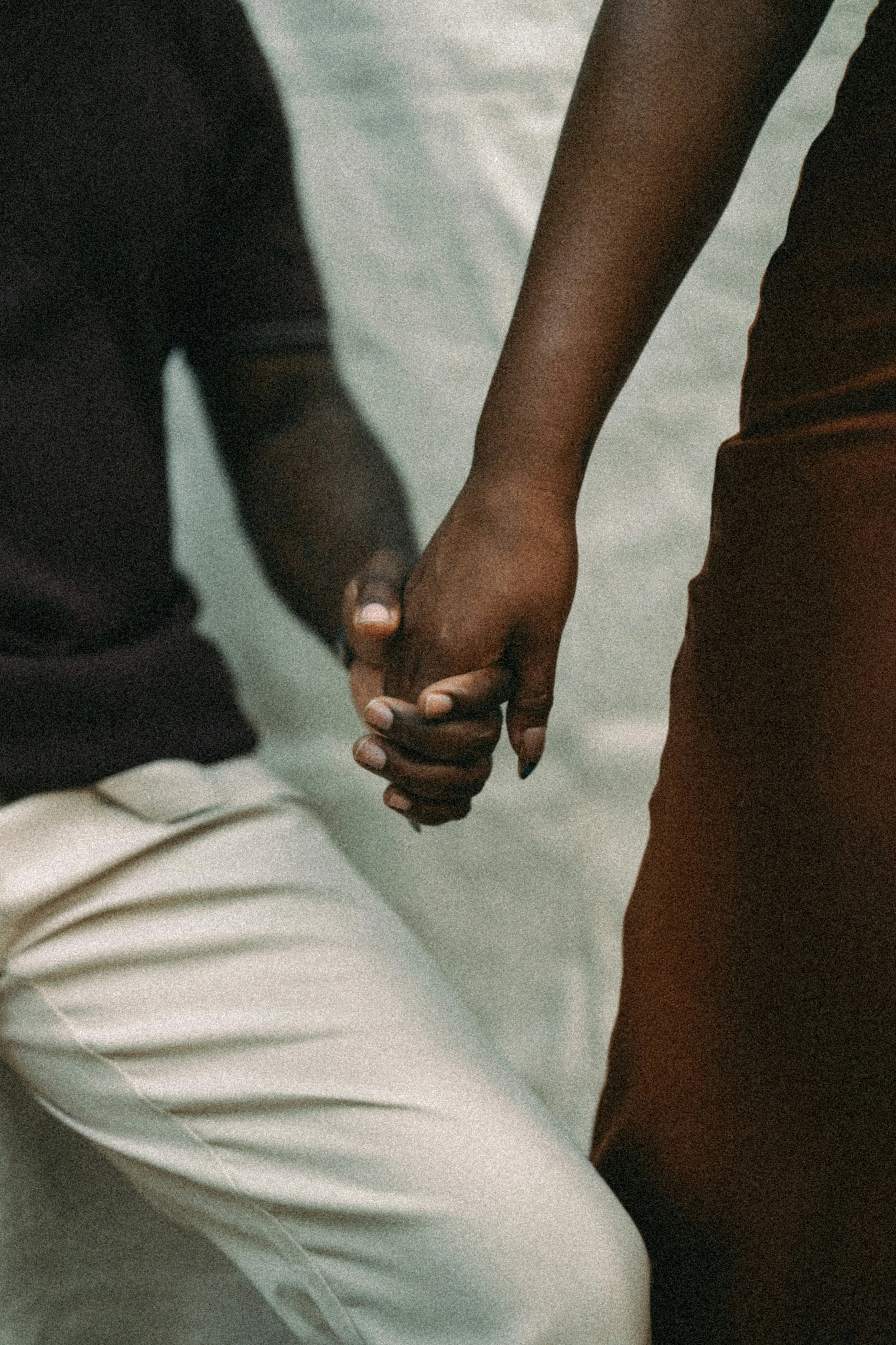 Two people holding hands, one with darker skin and the other with lighter skin.