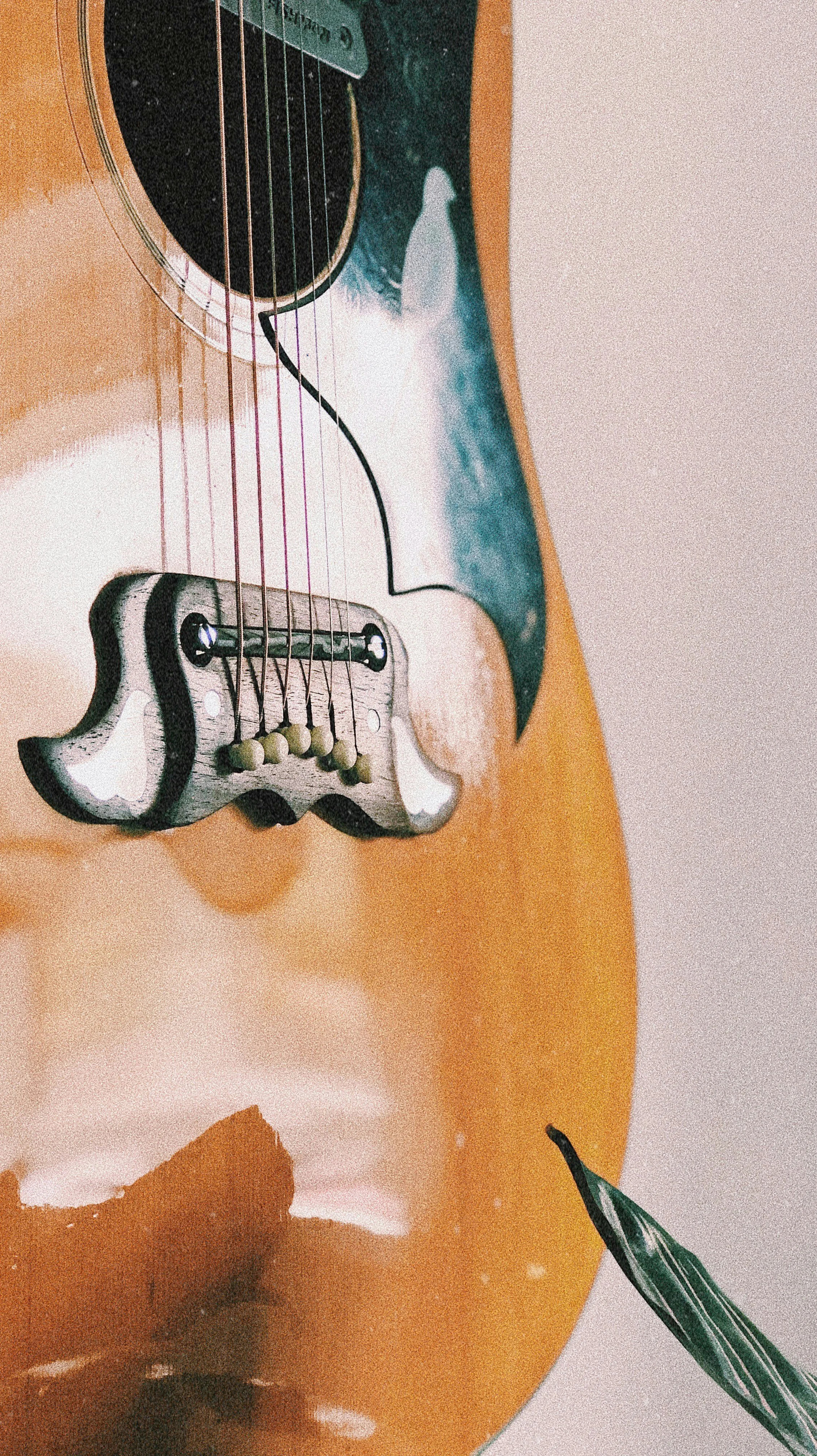 Close-up of an acoustic guitar with a small paintbrush resting on its body.