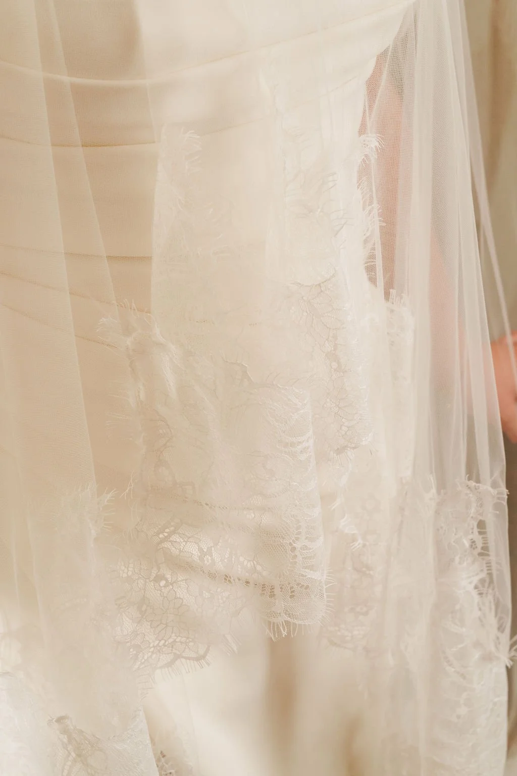 Close-up of a white lace wedding dress with intricate embroidery and sheer fabric.