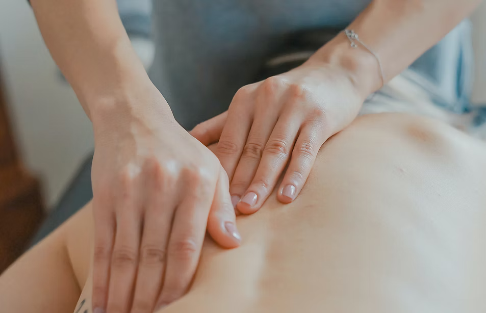 A person receiving a massage with hands pressing on their back.