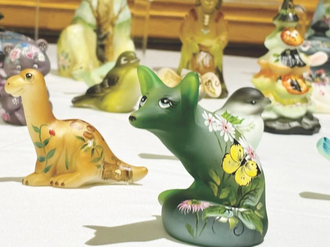 Colorful hand-painted Fenton animal figurines displayed at a vintage market.