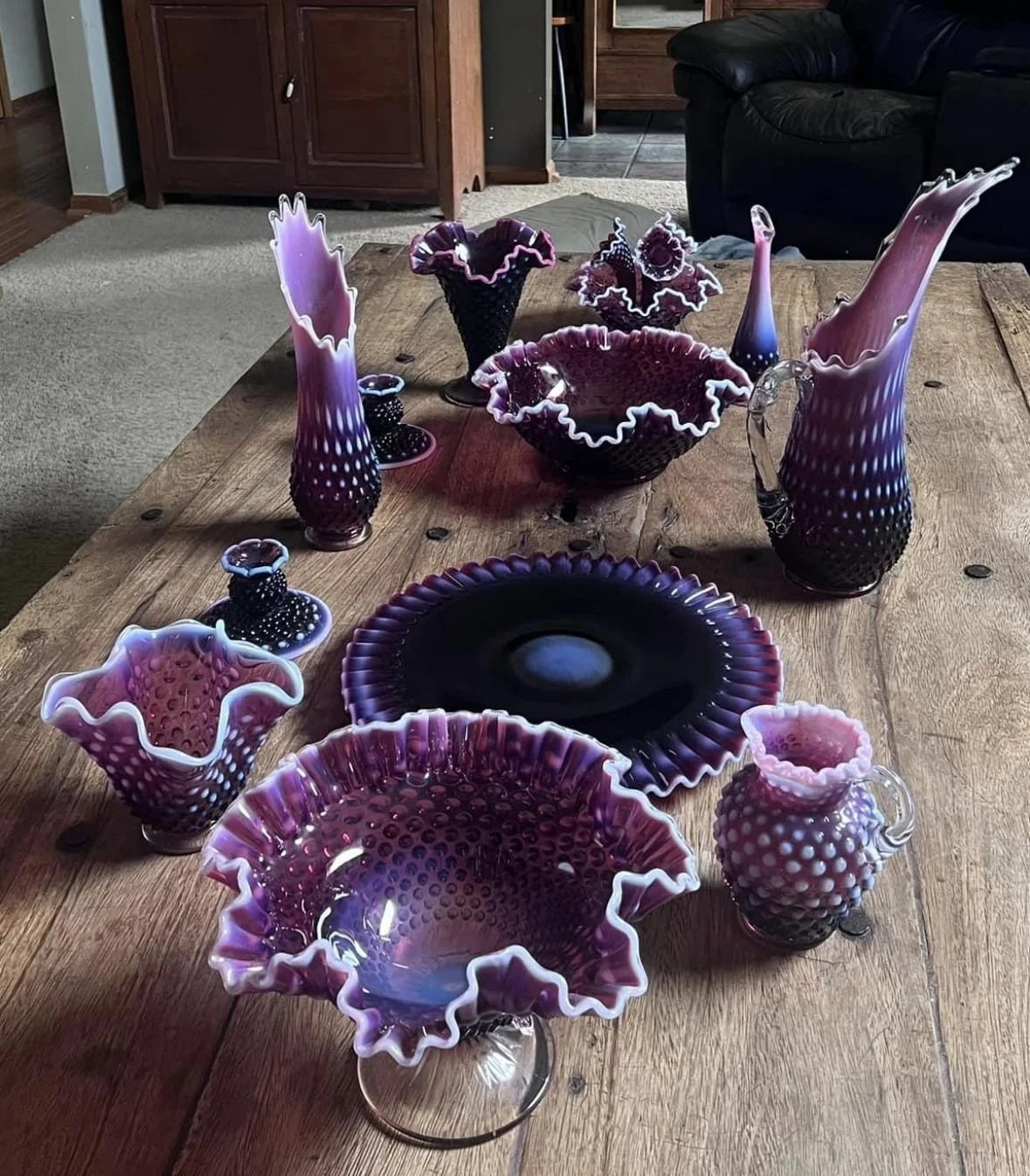 Purple vintage Fenton art glass collection arranged on a wooden table