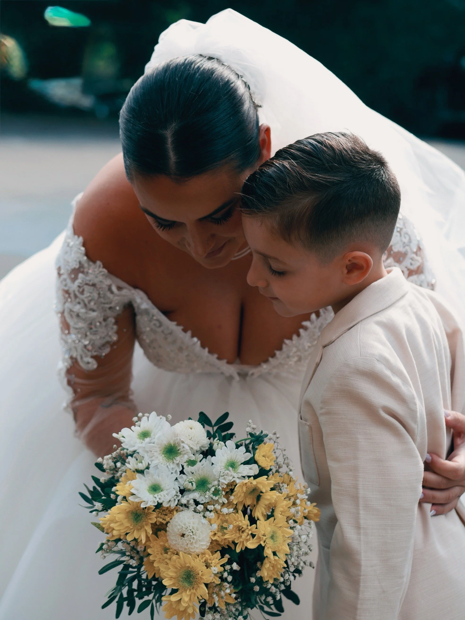 Une femme en robe de mariage et un garçon regardent un bouquet de fleurs lors d'une cérémonie.