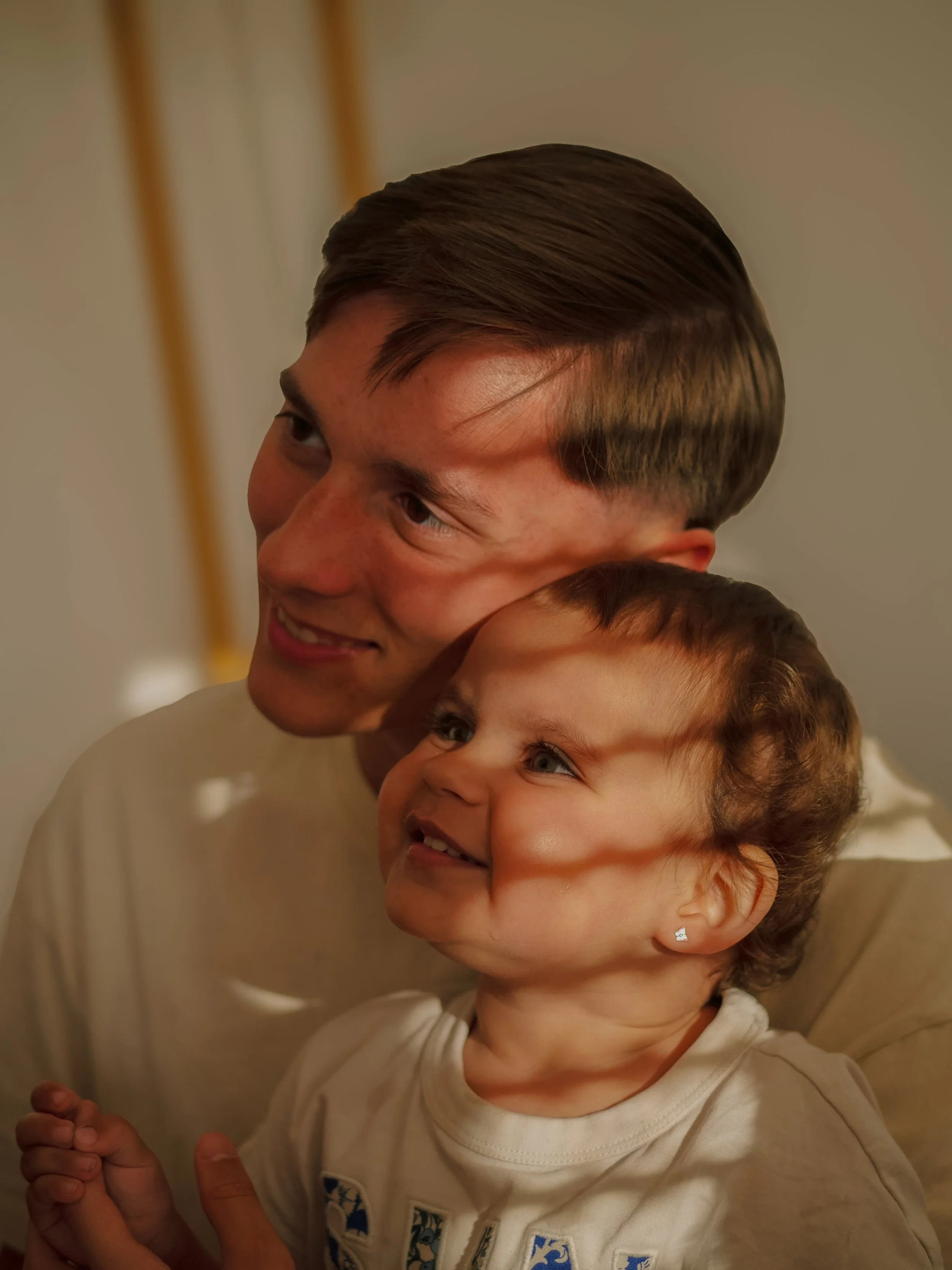 Un homme et un jeune garçon souriant, en train de se faire un câlin ou une accolade.