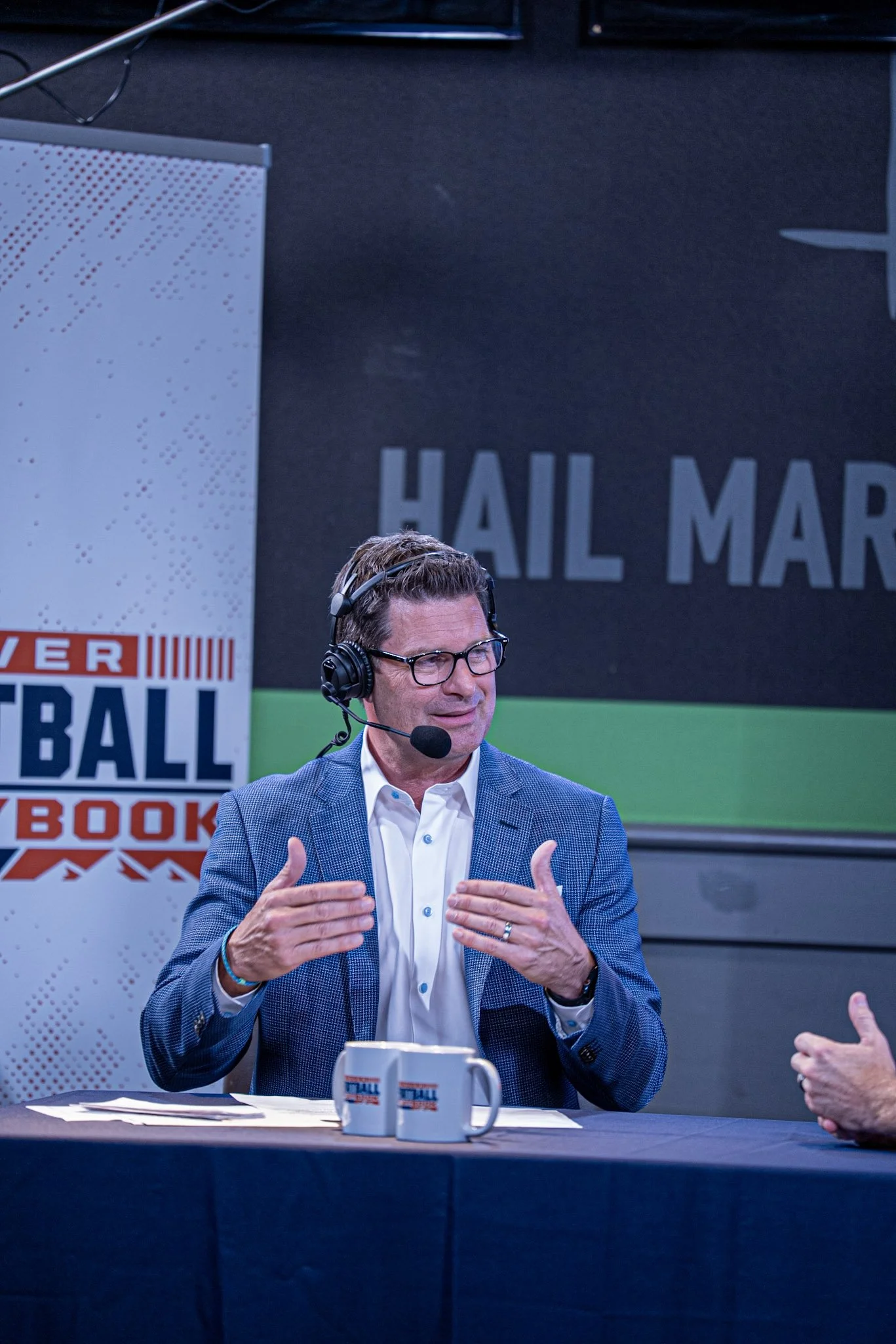 Host Arran Andersen on stage speaking during the first live taping of Denver Football Playbook at Dave & Busters - Westminster