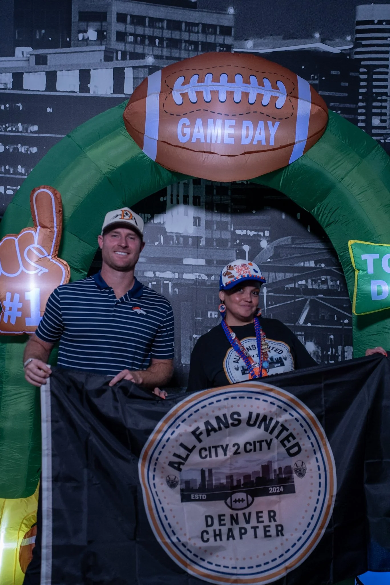 Denver Football Playbook guest Wil Lutz holds a flag with a fan at Dave & Buster's in Westminster