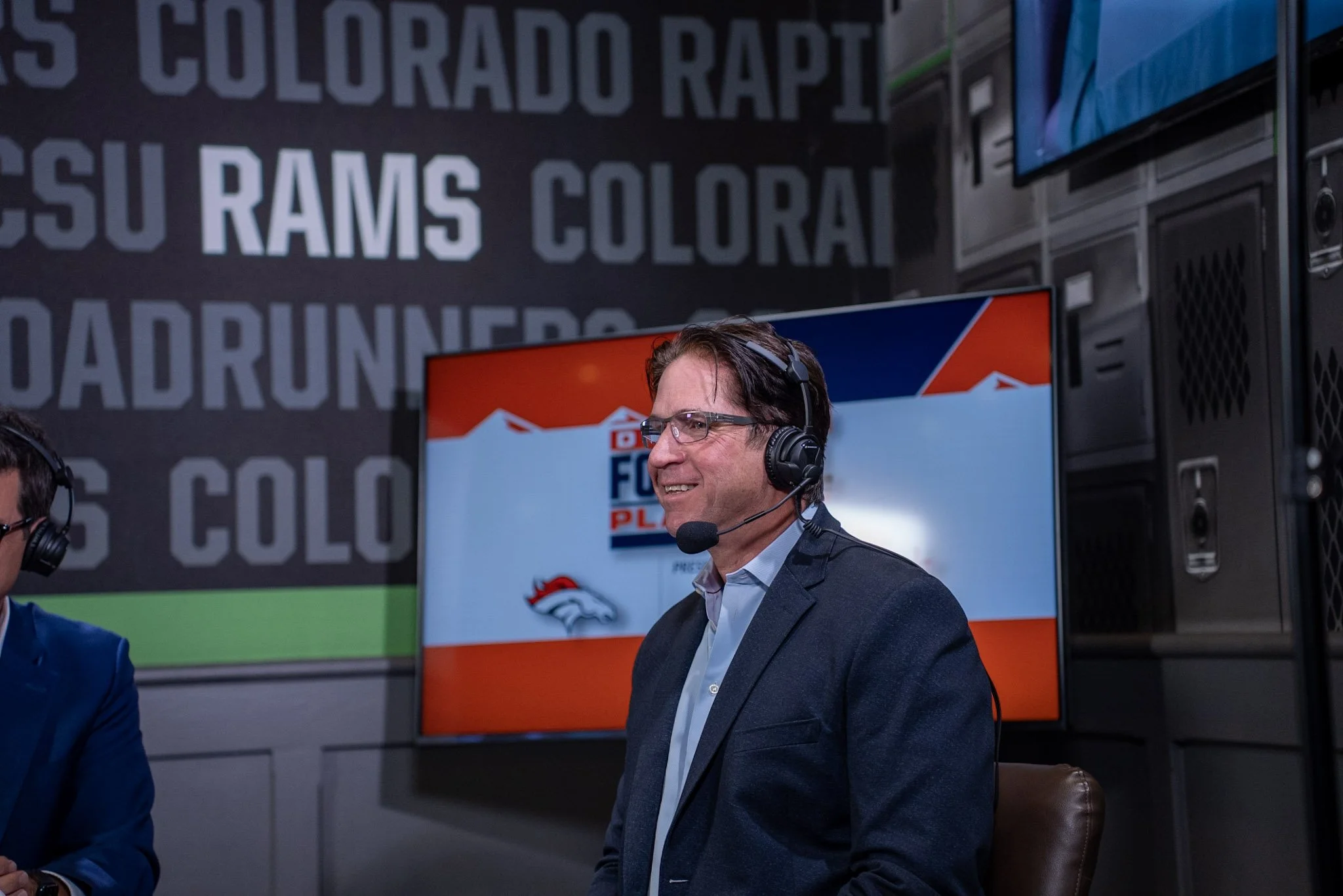 Ed McCaffrey smiles while speaking with Arran Andersen during Denver Football Playbook LIVE in Denver.