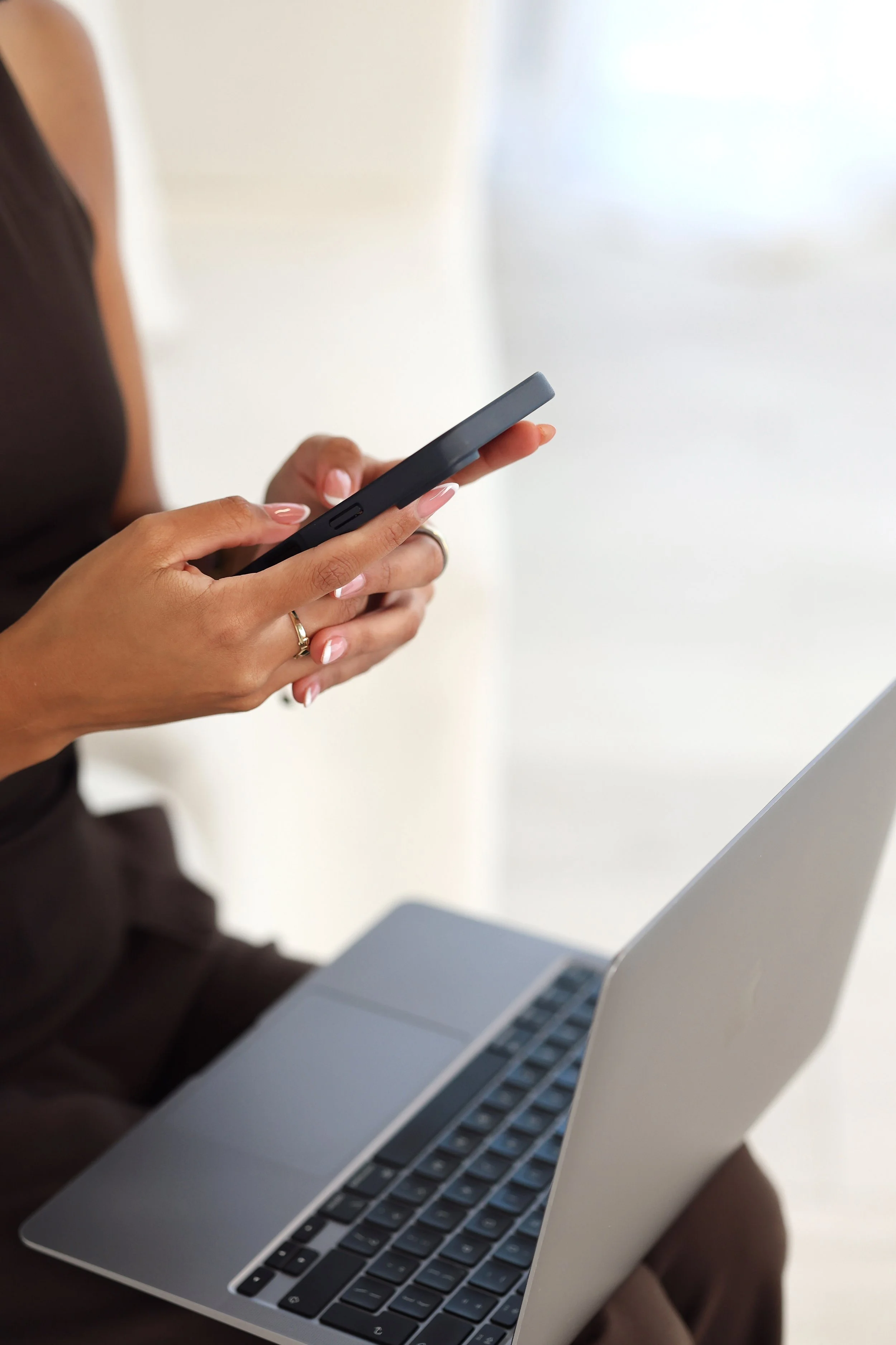 Close-up of Summer using her phone beside an open laptop