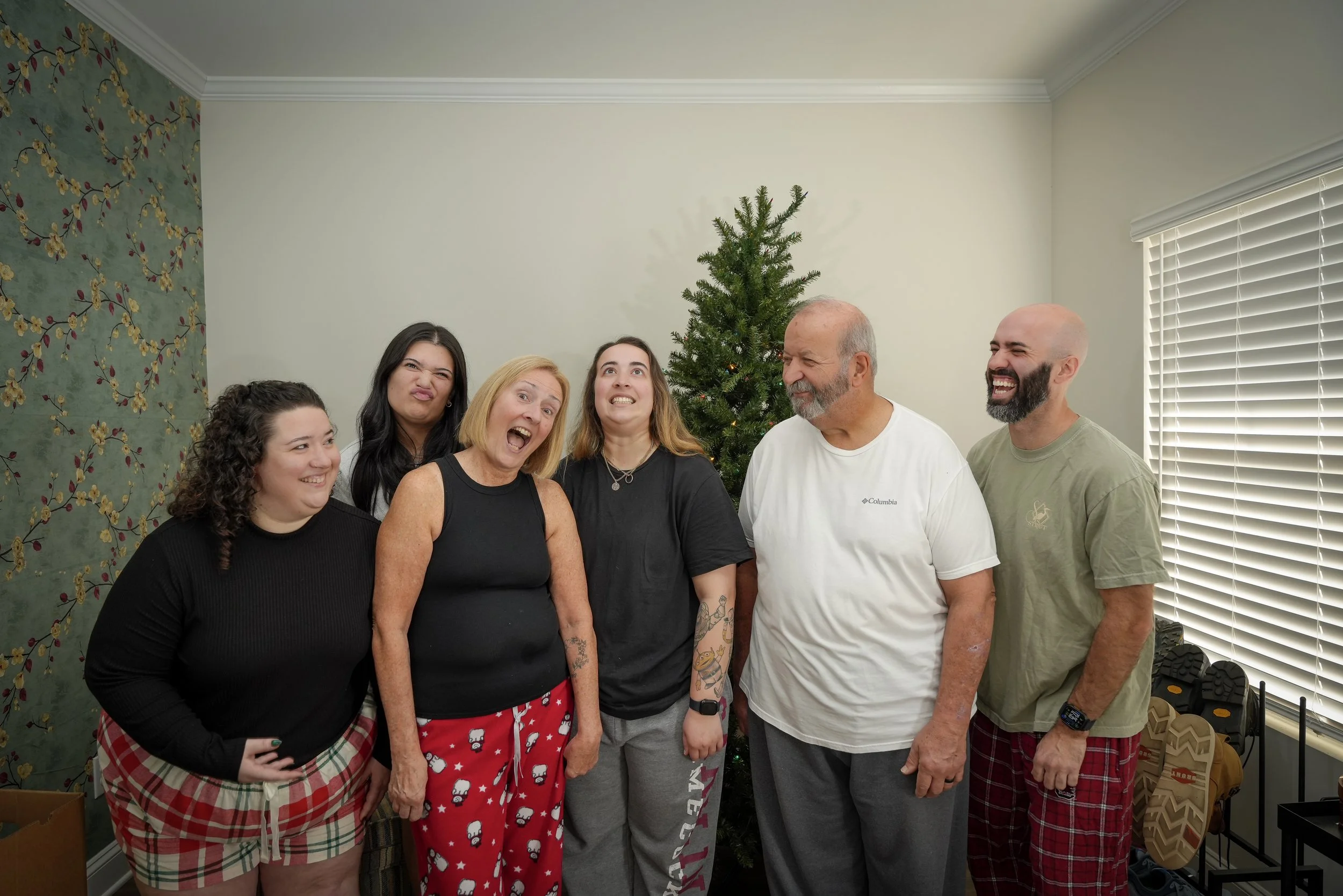 Family of six laughing together in pajamas beside a Christmas tree, family photographer Fort Mill SC