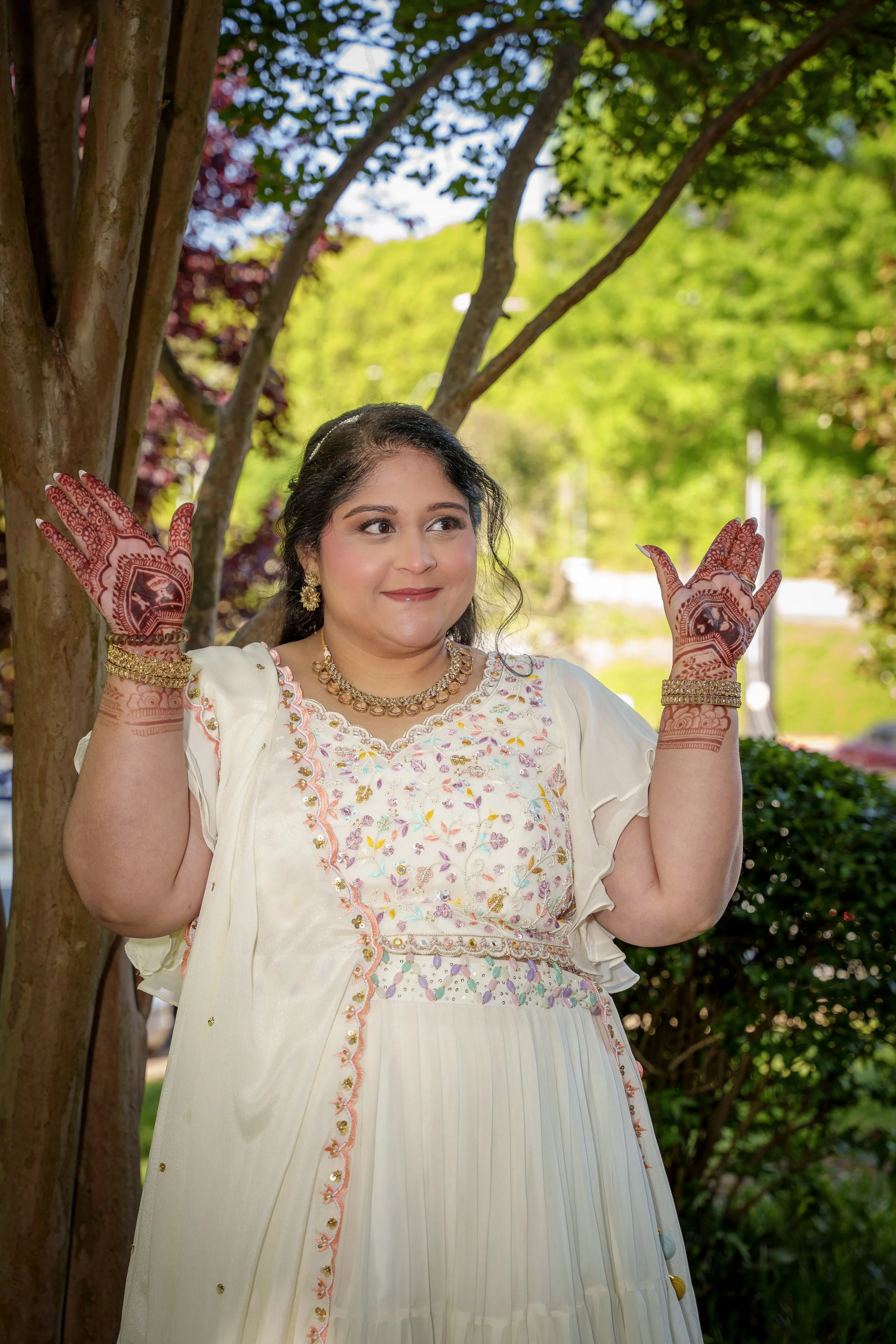 Woman raising henna-decorated hands in dappled afternoon light, cultural portrait photography Charlotte NC