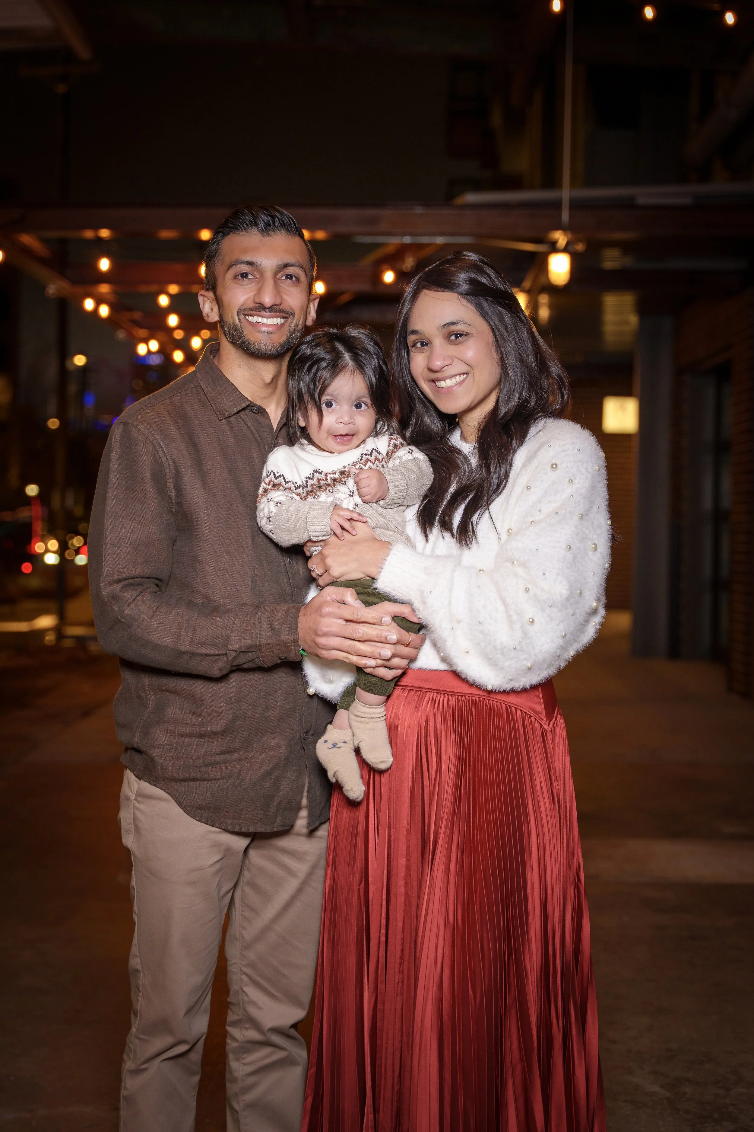 Family of three under warm string lights at night, evening family photography Charlotte NC
