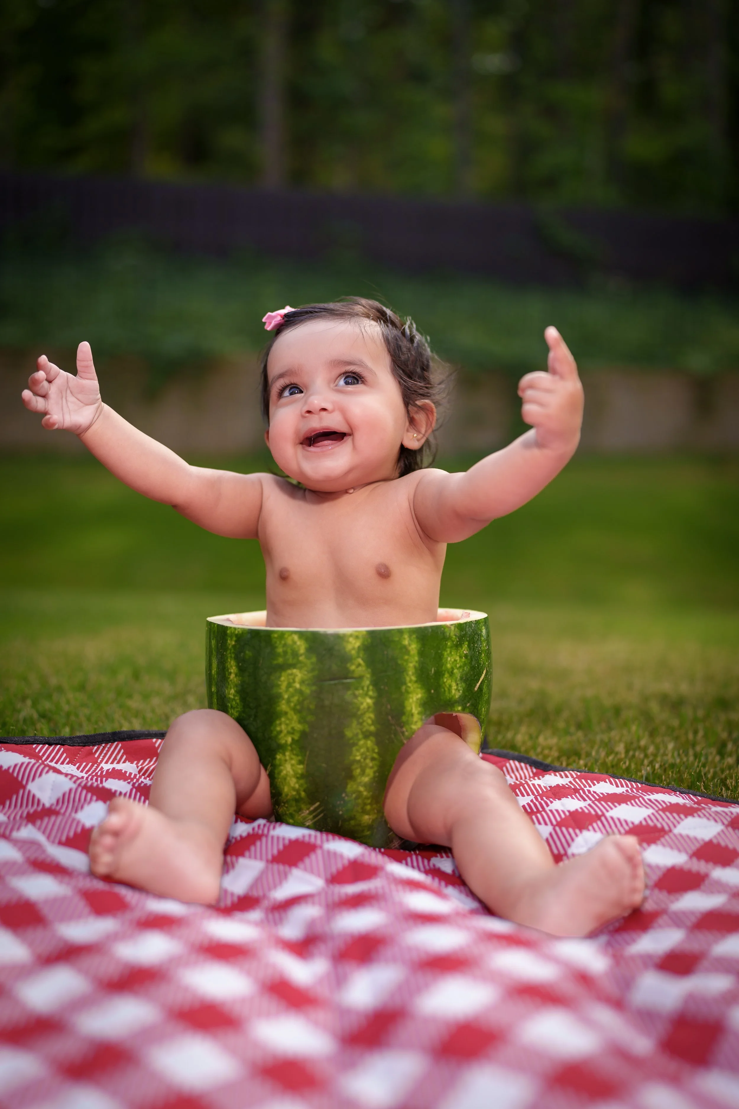 Baby sitting inside a hollowed watermelon with arms raised, creative baby photography Fort Mill SC