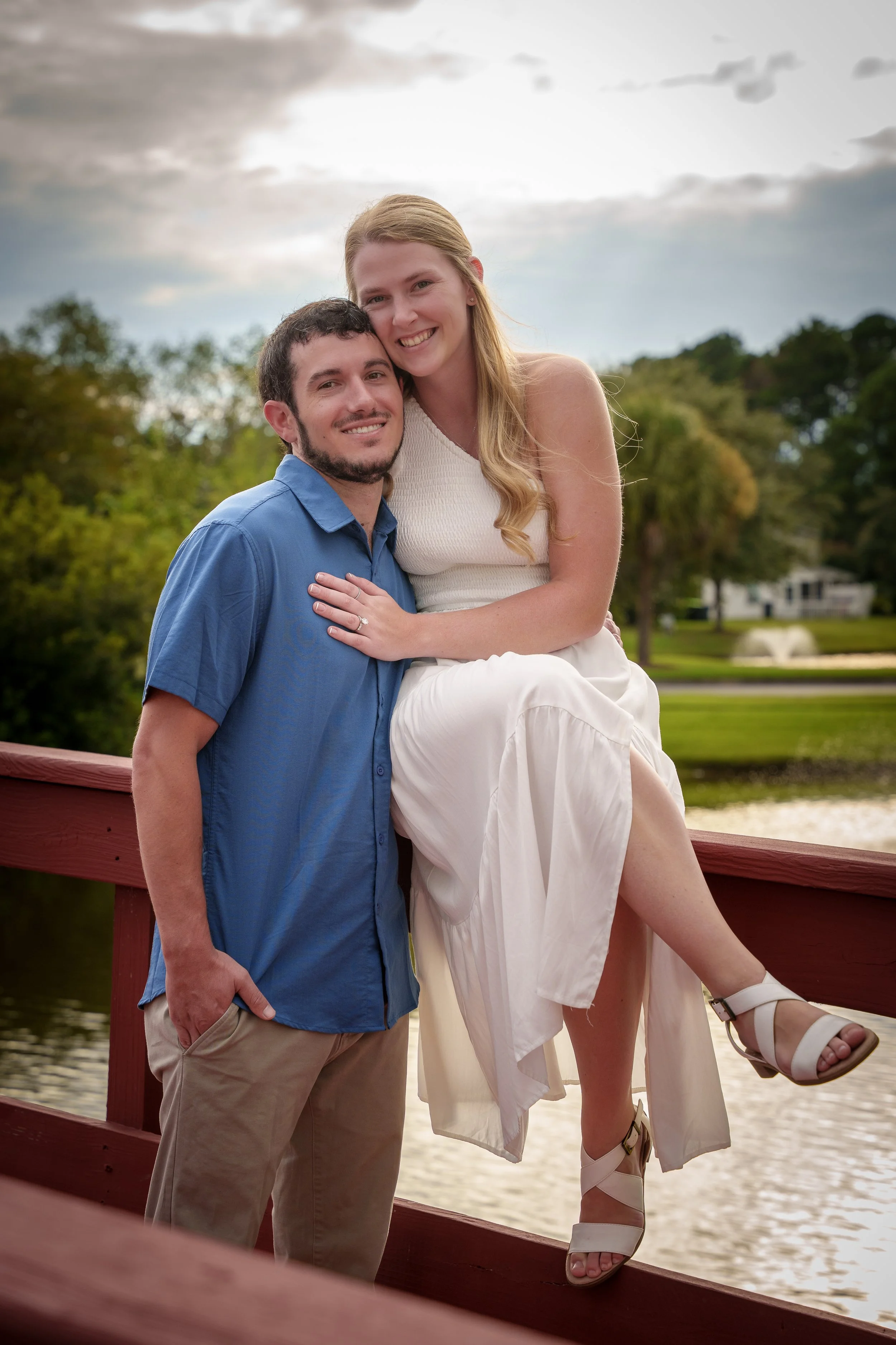 Couple standing close together on a red wooden bridge, couples photography session Charlotte NC