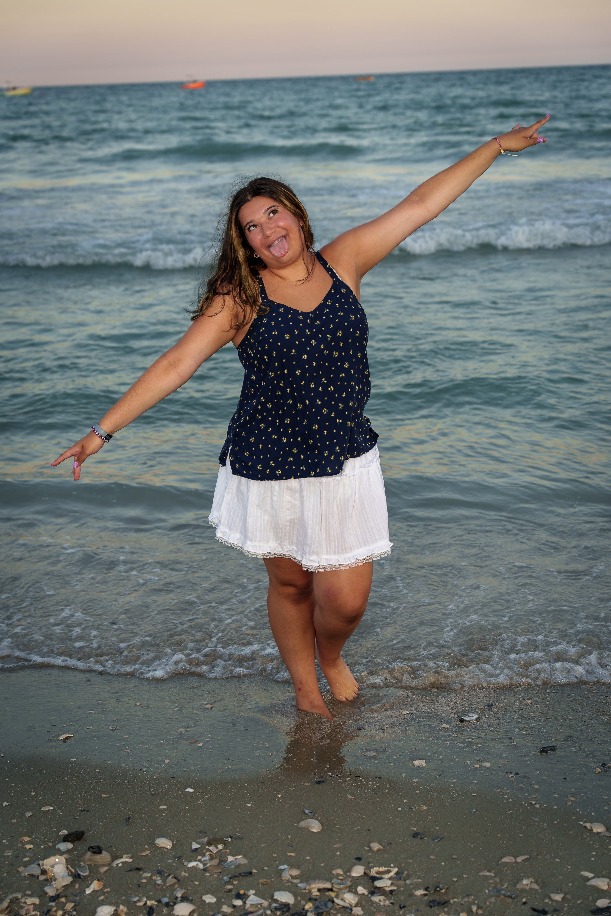 Girl on the beach with arms outstretched mid-laugh at golden hour, beach portrait session South Carolina