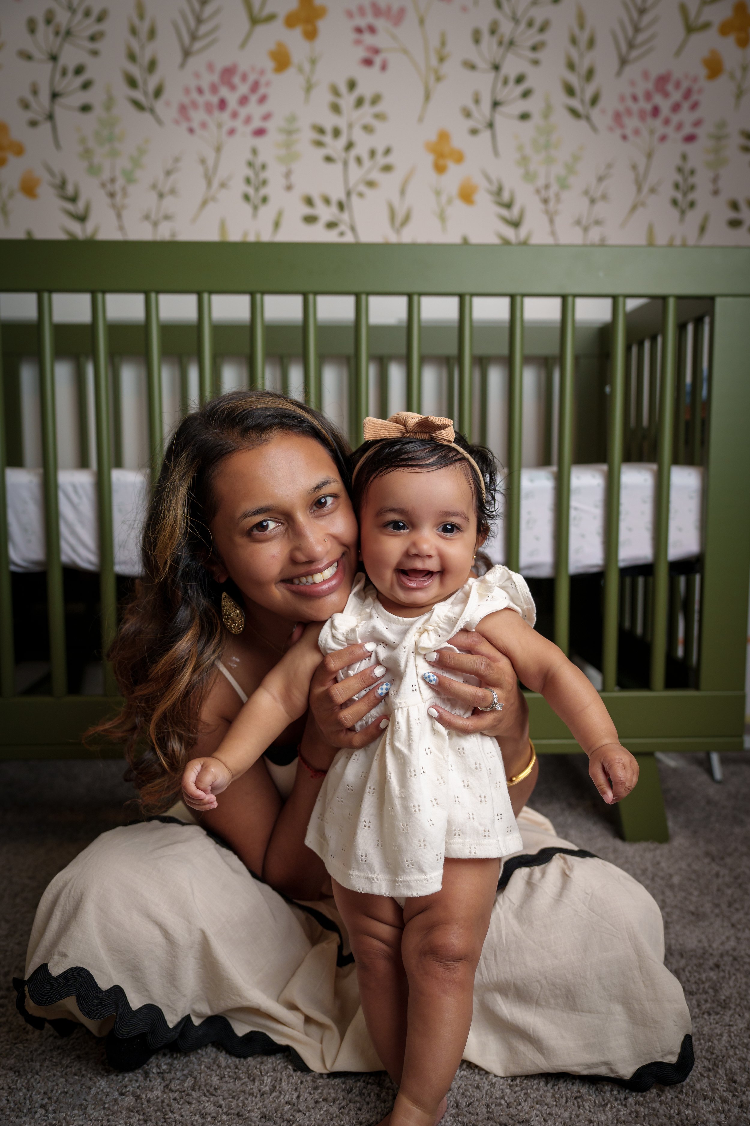 Mother holding her baby beside a green crib, motherhood photography session Fort Mill SC