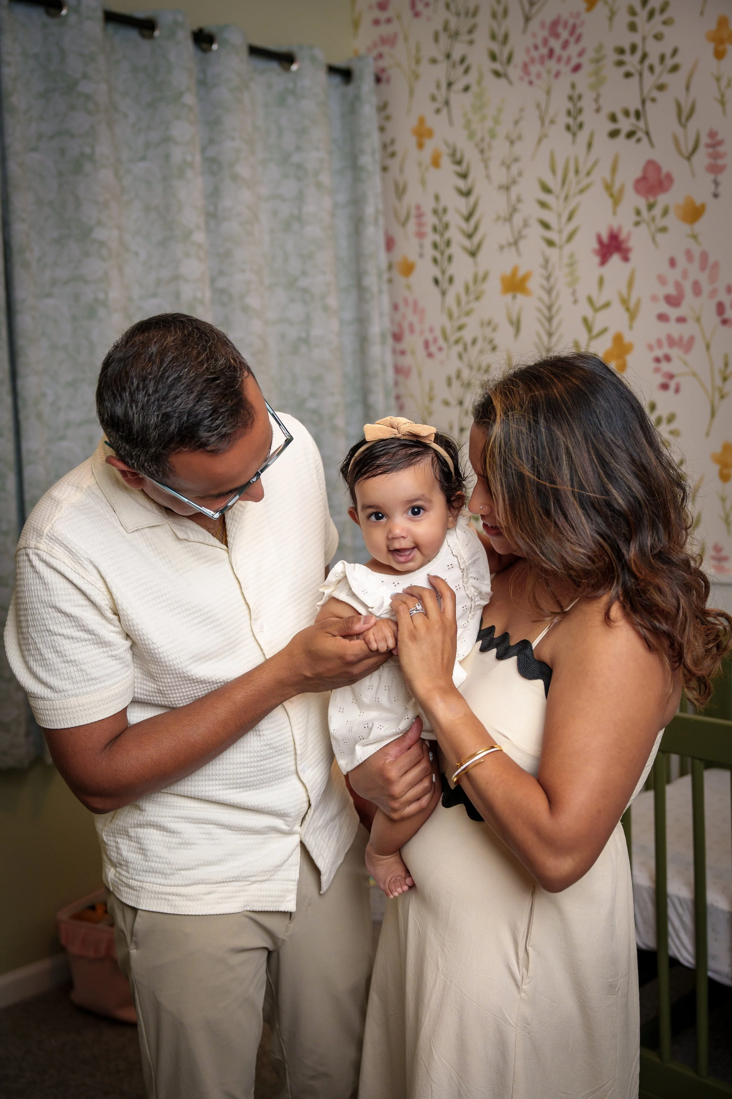Parents holding their baby in a floral nursery, in-home family photographer Fort Mill SC