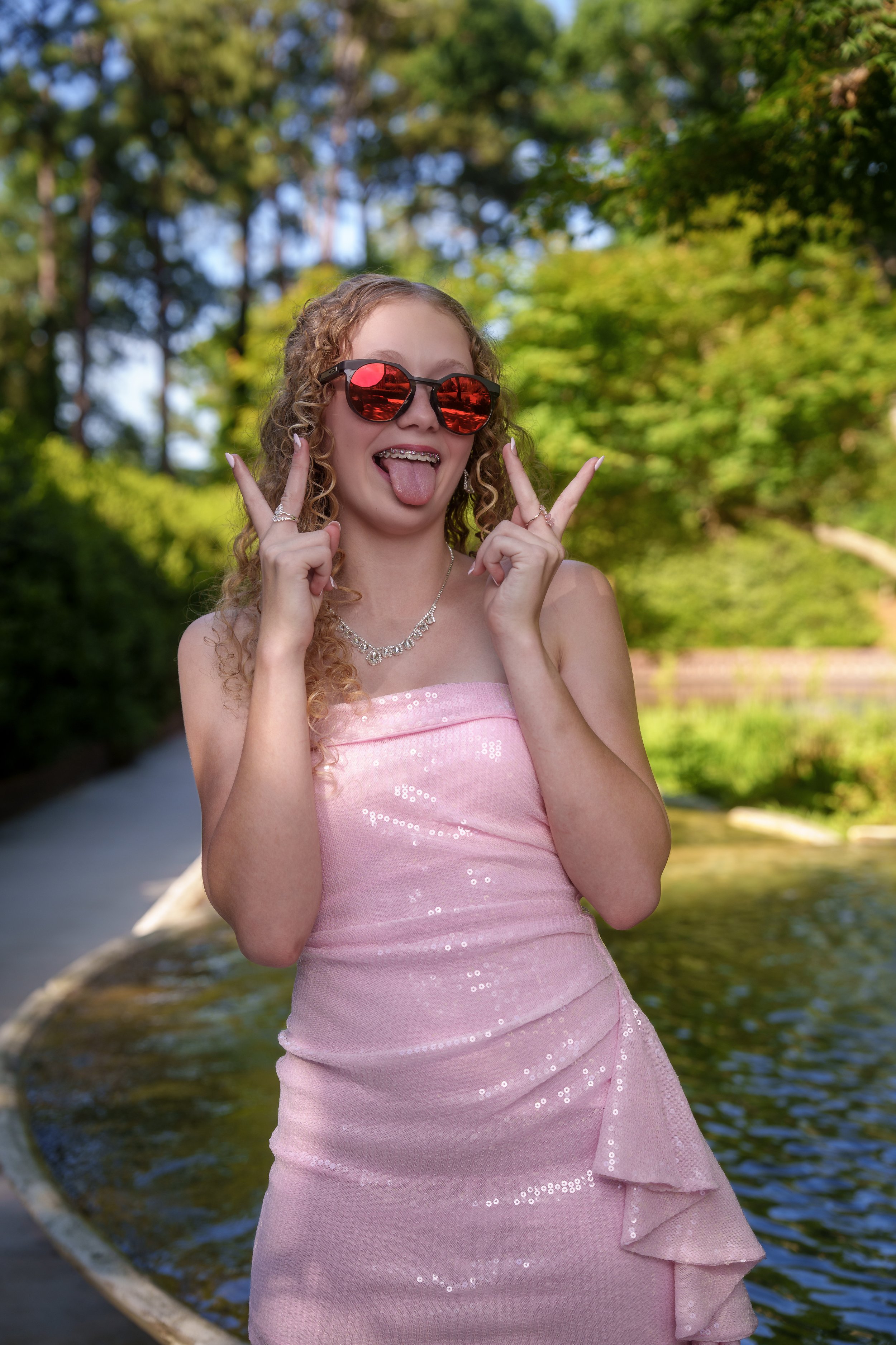 Girl in a pink dress pulling a face behind red sunglasses, personality-driven portrait session Charlotte area