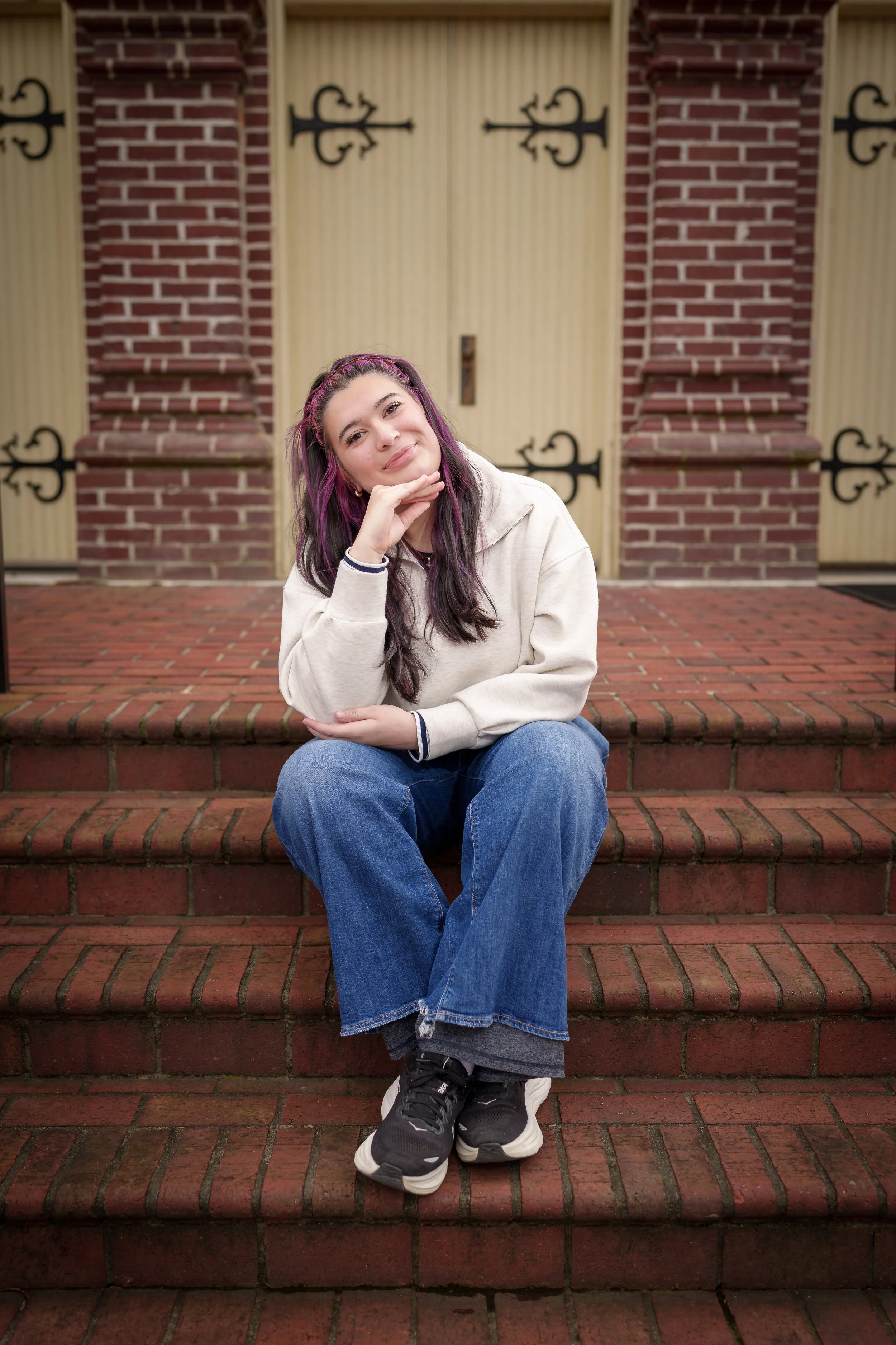 Young woman with purple hair seated on red brick steps, environmental portrait photography Fort Mill SC