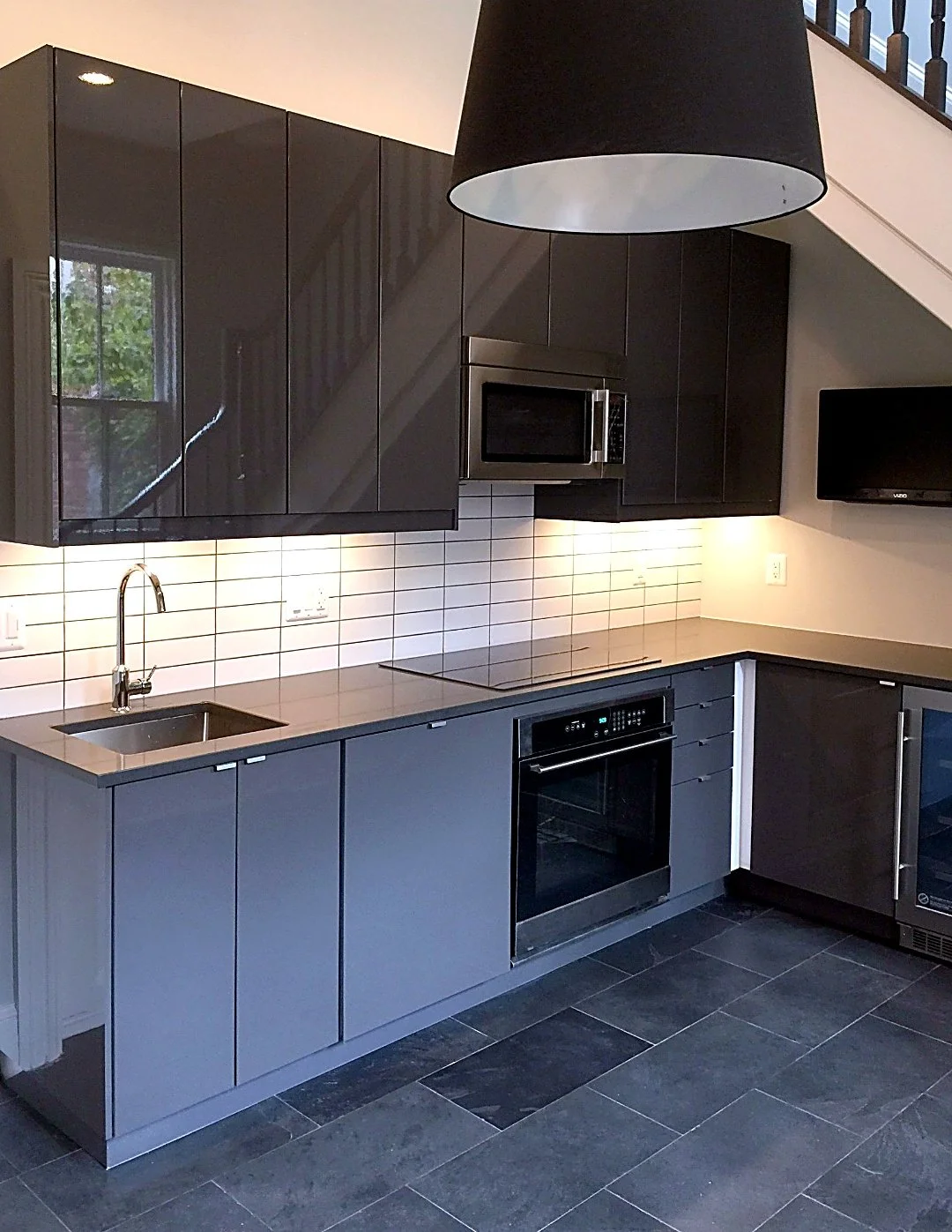 Modern grey kitchen with white subway tile, a built-in wall oven and slate floor