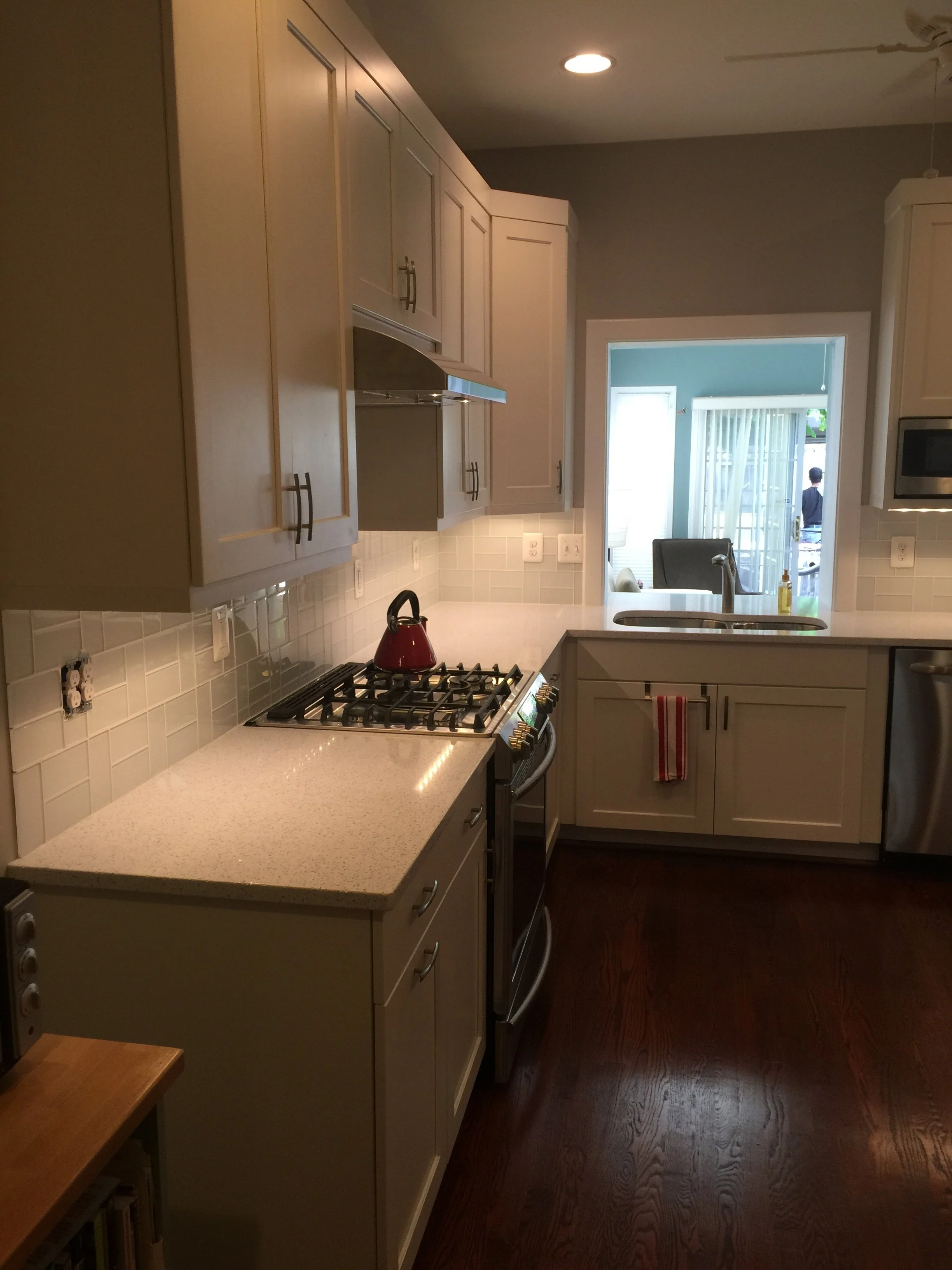 Cream painted kitchen with a tiled backsplash, gas range and dark hardwood floors