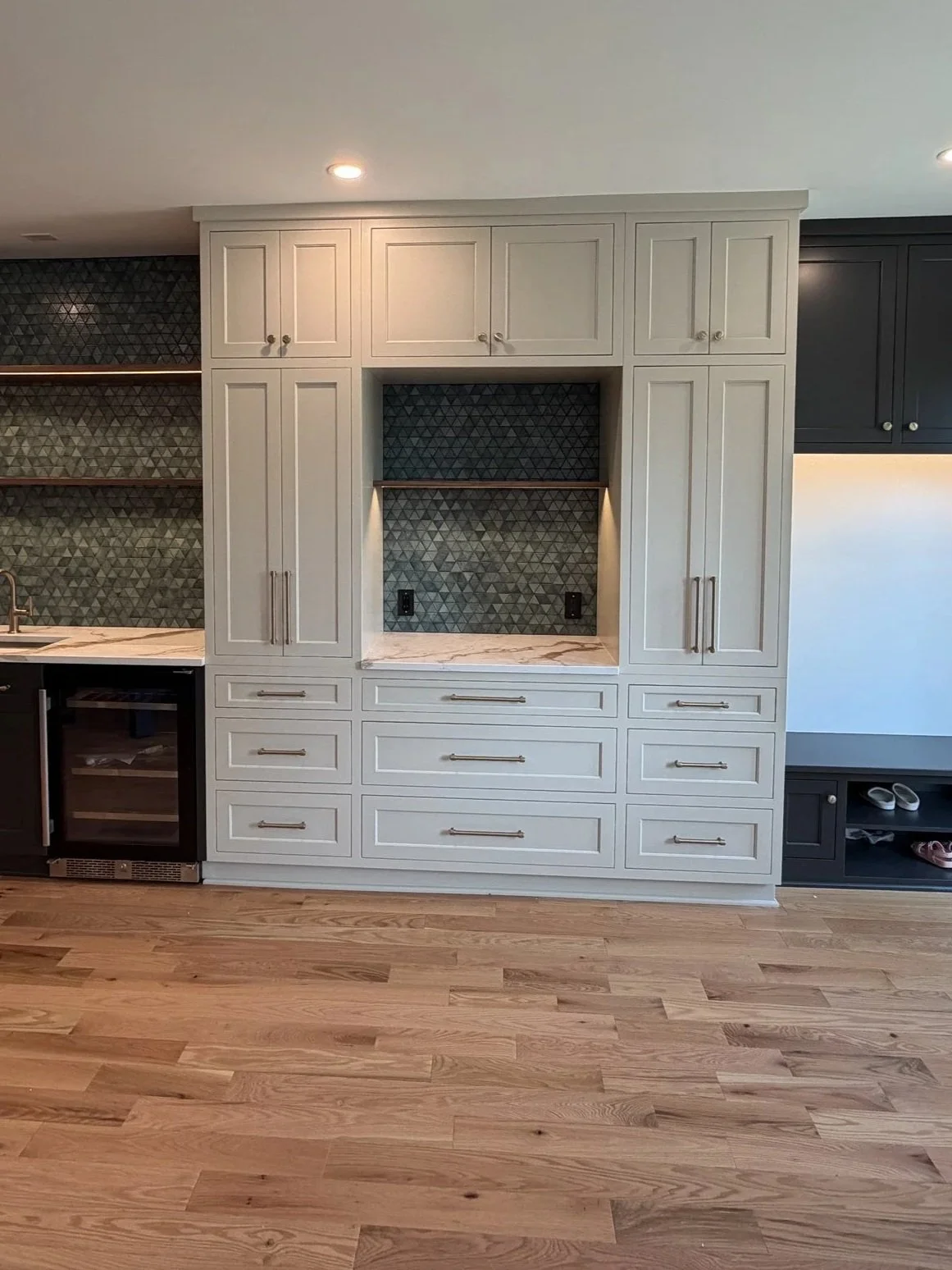 Built-in beverage bar in cream cabinetry with a mosaic tile back and undercounter wine fridge
