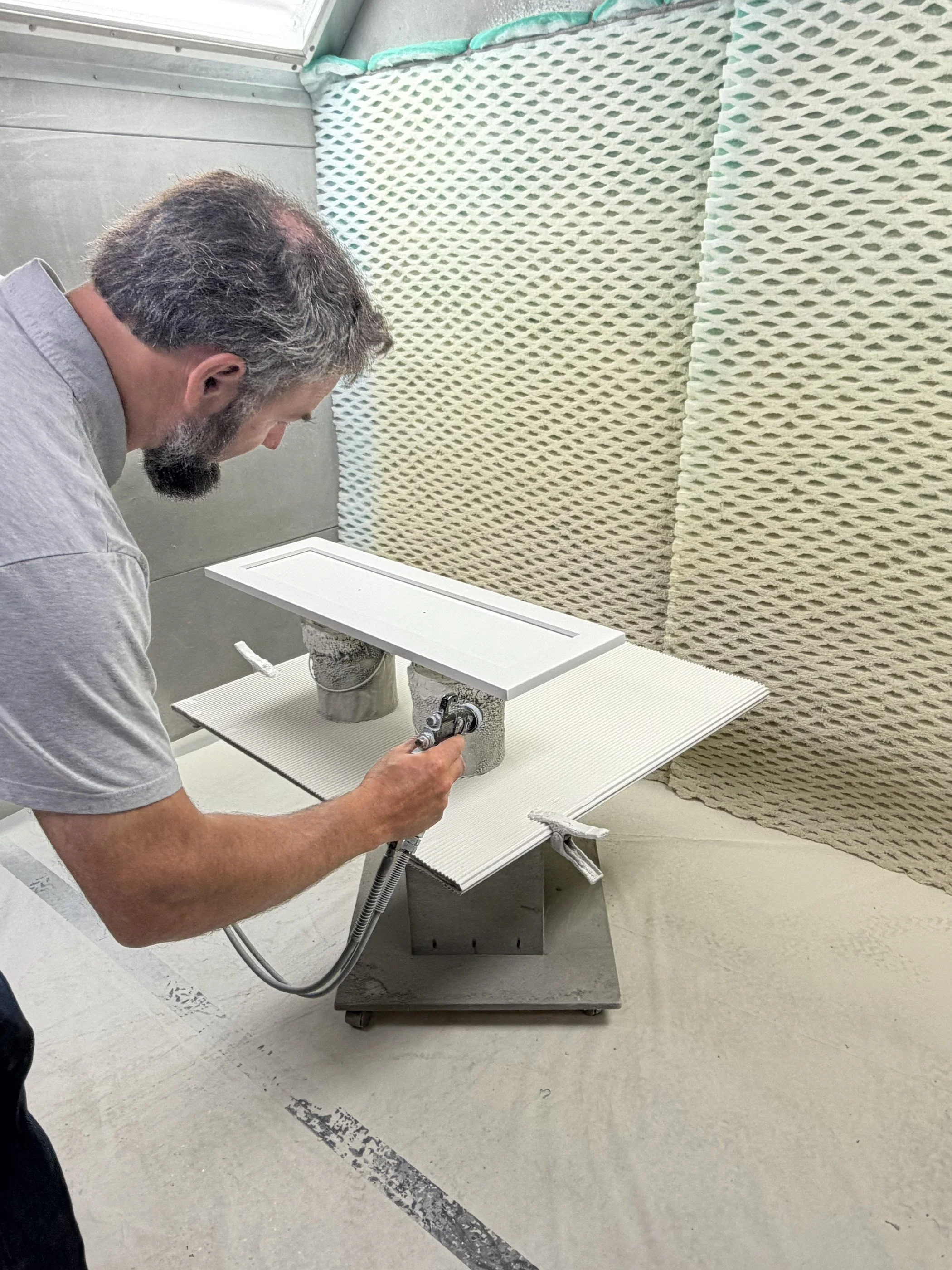 Cabinet door being spray-finished in the shop's finishing booth