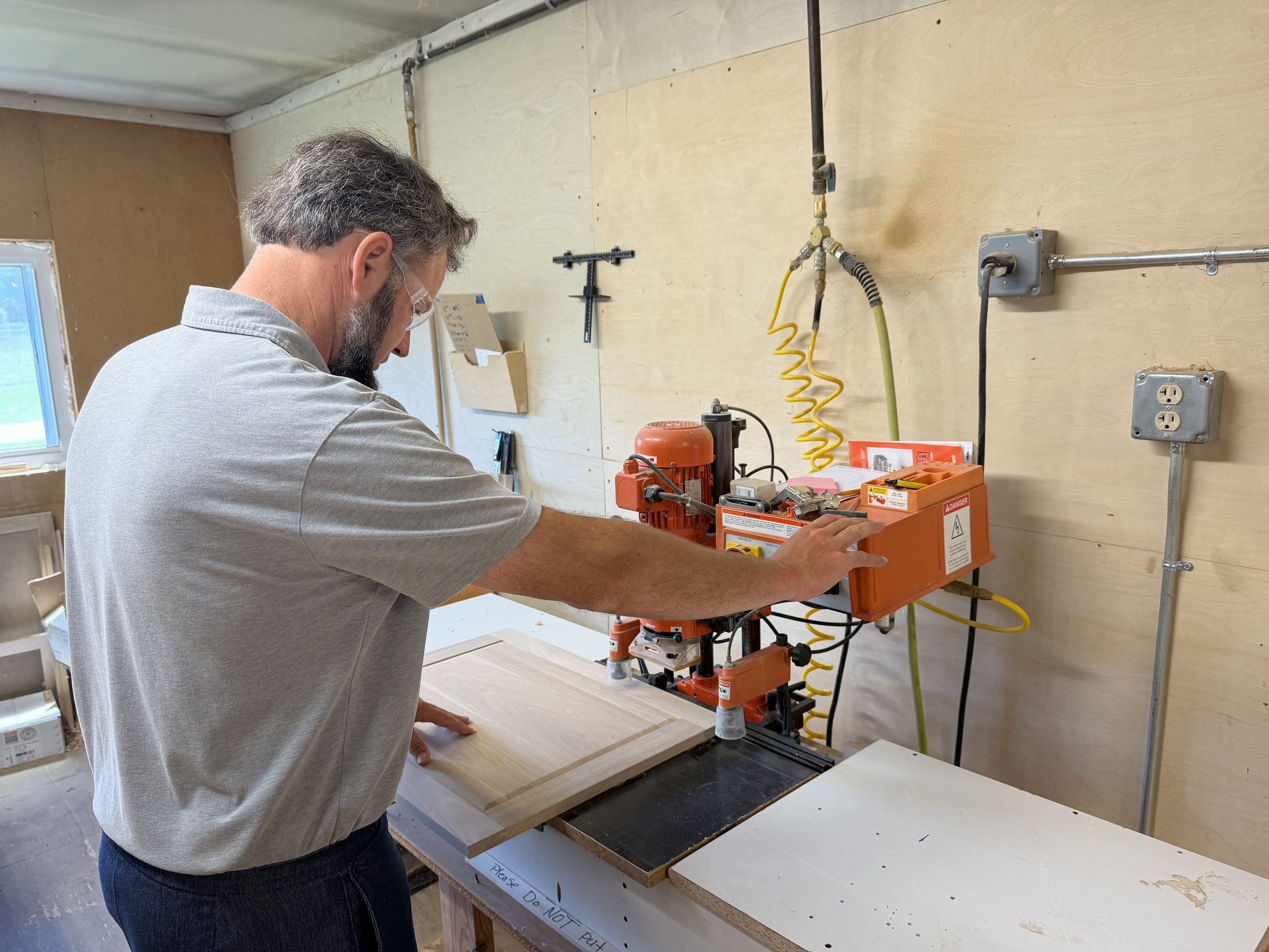 Craftsman routing a cabinet panel in the workshop