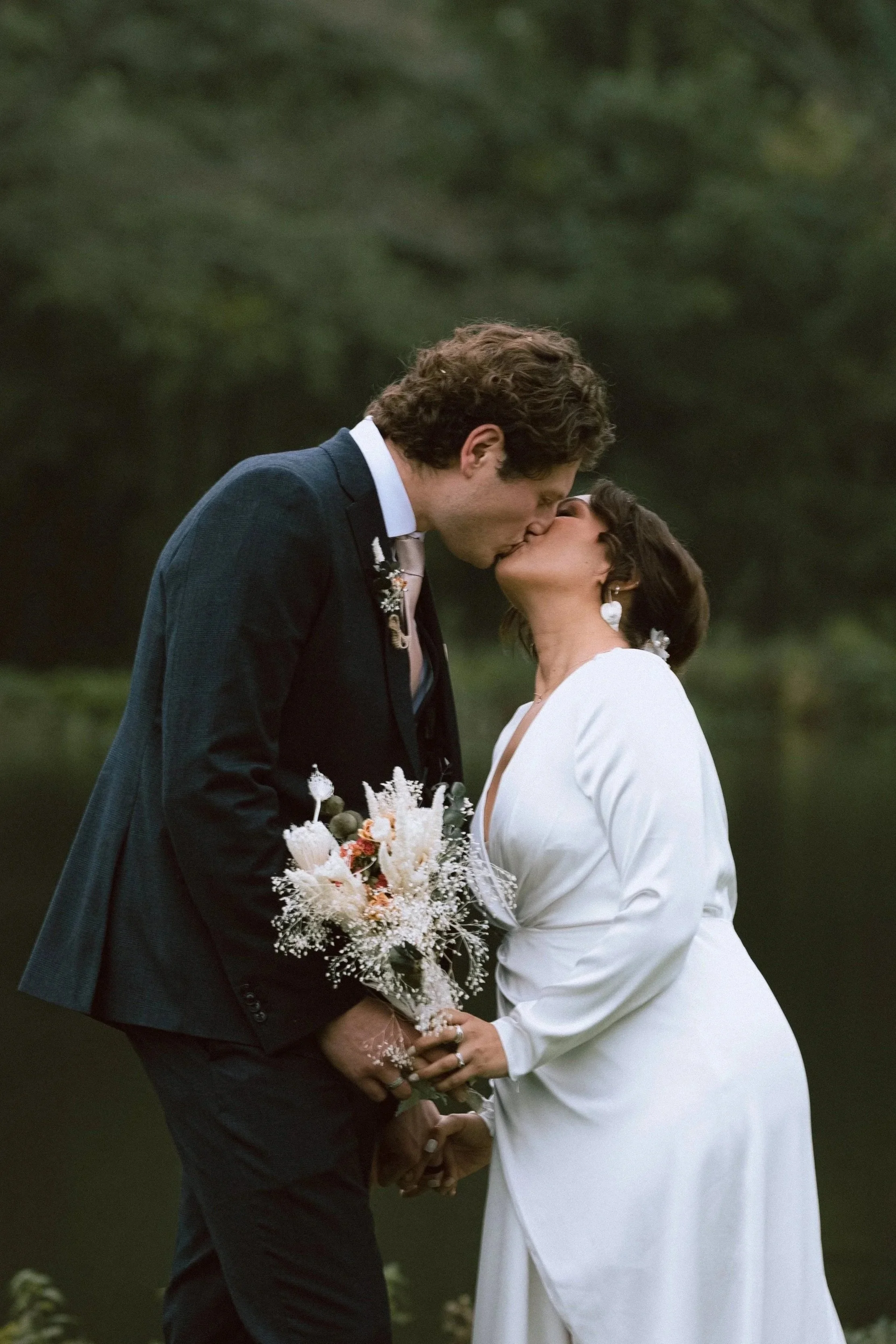 Bride and groom sharing a kiss surrounded by greenery at their Suffolk wedding