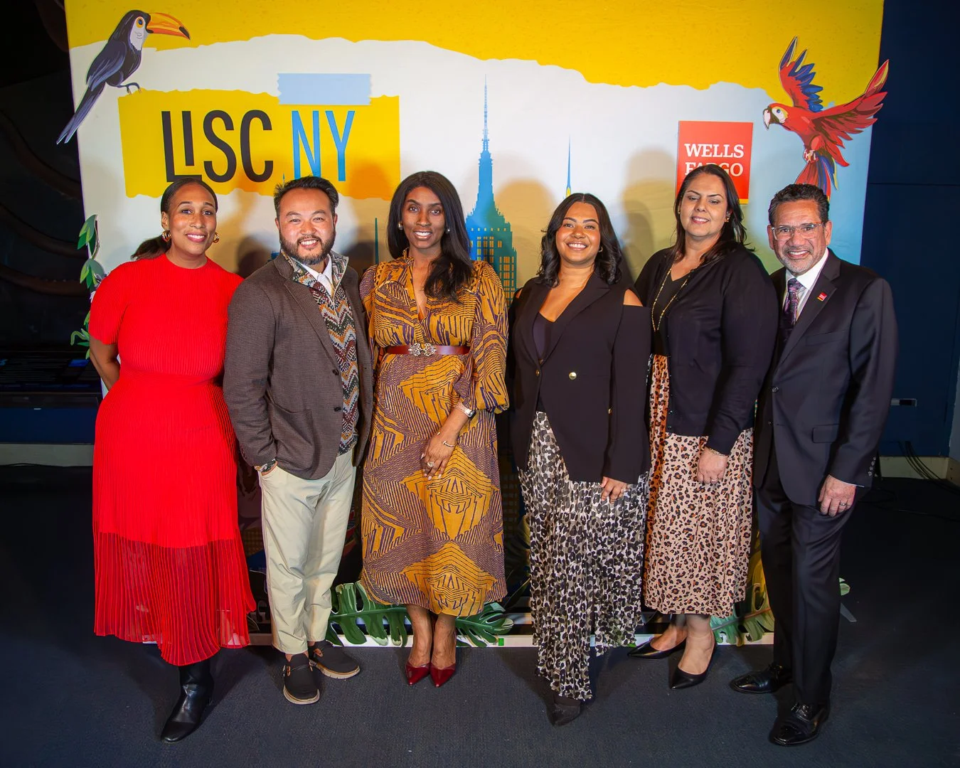 Six diverse professionals standing together at an event, with a backdrop featuring the text 'LSC NY' and logos of a toucan, a parrot, and Wells Fargo.