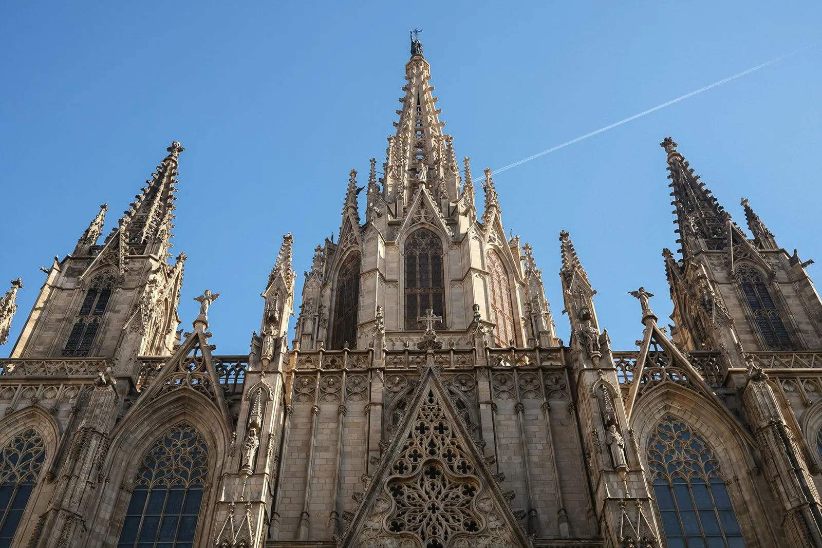 Front view of a gothic cathedral with ornate details and tall spires against a clear blue sky.