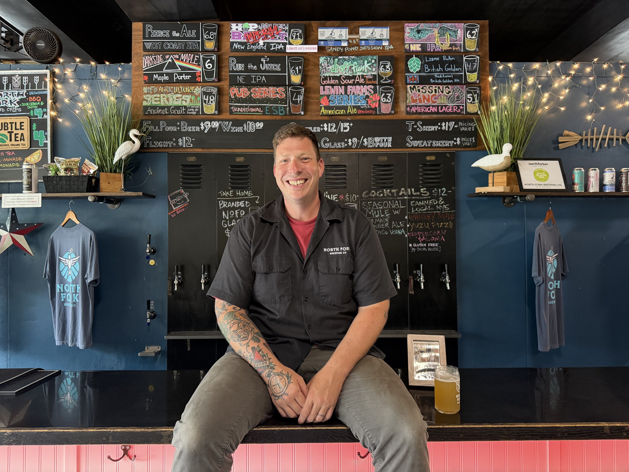 Peter Barraud, head brewer at North Fork Brewing Co., smiling at the bar in the Riverhead taproom.
