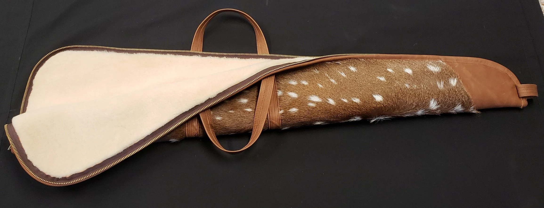 A gun case with a brown leather exterior, partially unzipped, reveals a white, fuzzy lining and a fur pattern with white spots on a brown background.