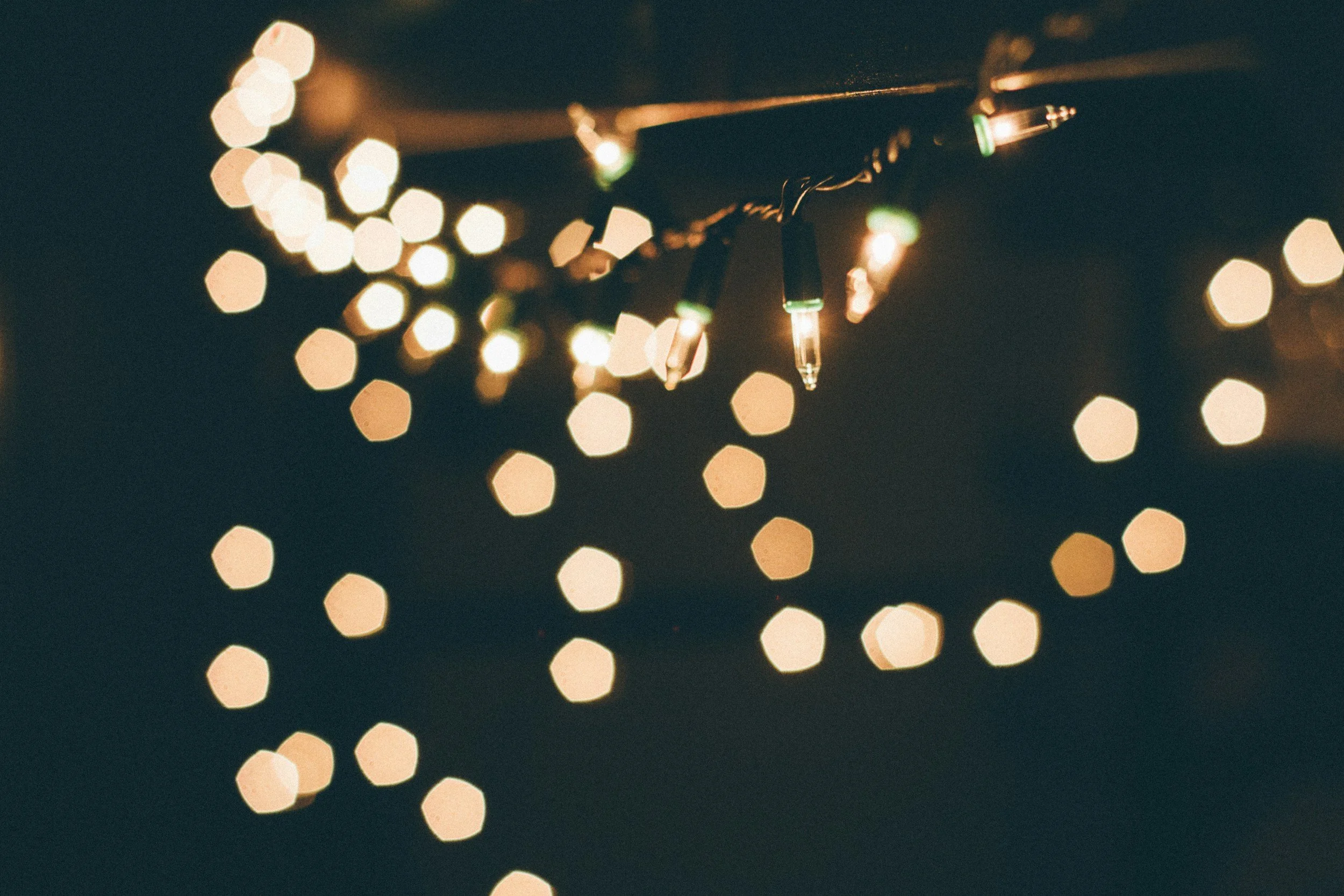 Close-up of string lights with a bokeh effect in the background, nighttime scene.