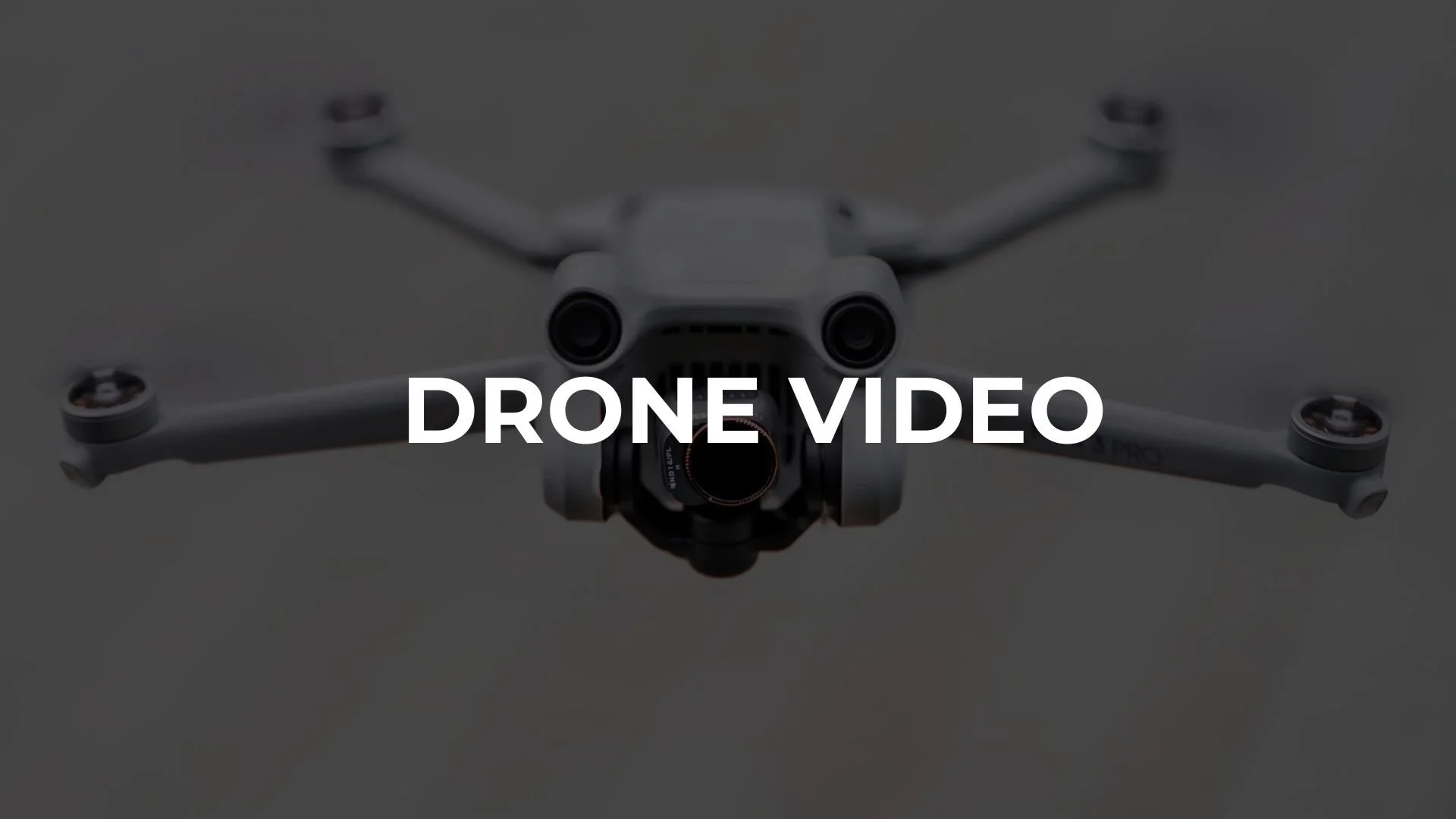 A white drone with four propellers captured from below, with the text "DRONE VIDEO" overlayed in the center.