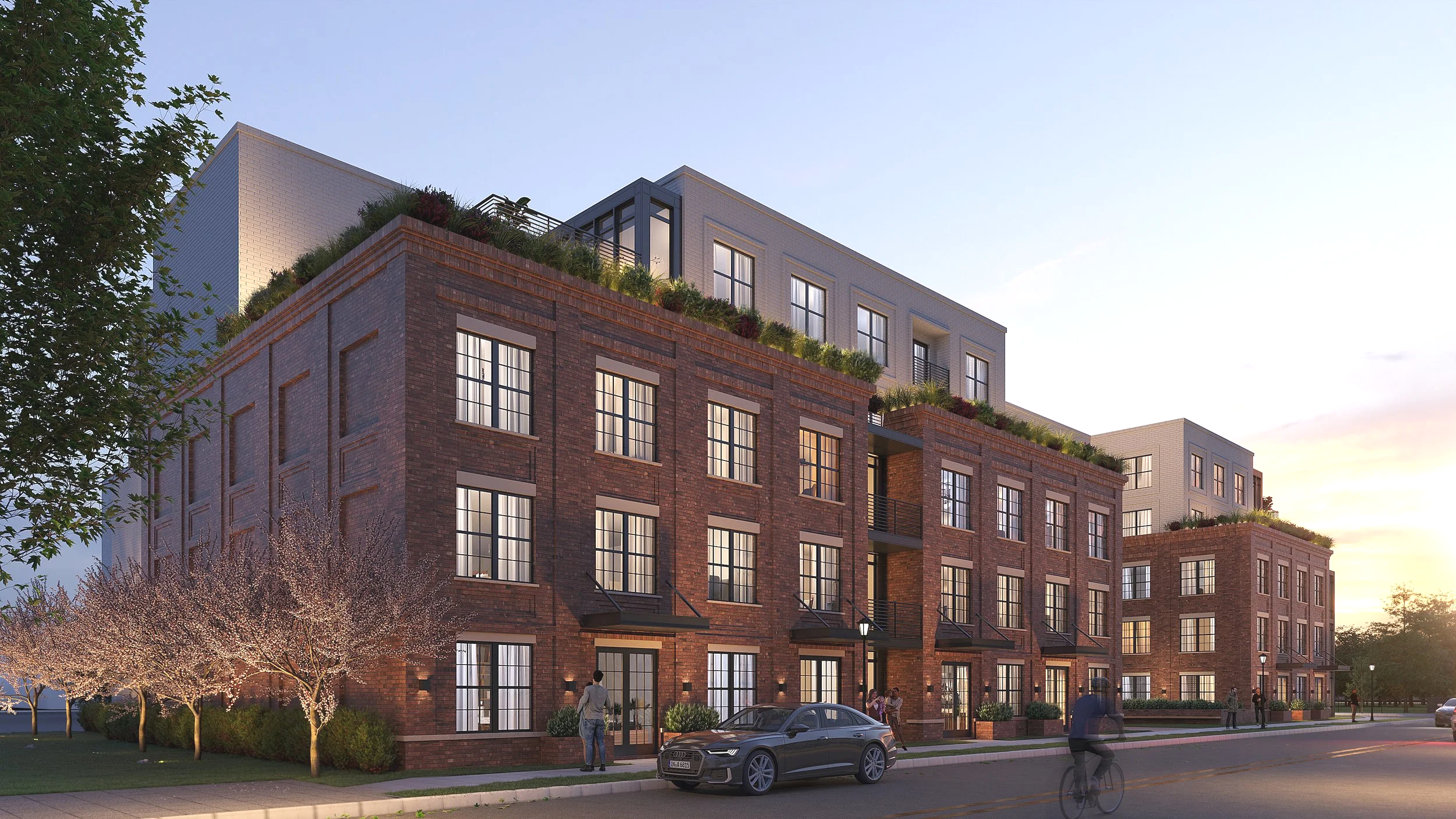 Modern multi-story residential building with brick and light-colored siding, large windows, rooftop gardens, and people outside during sunset, with trees and a car parked nearby.