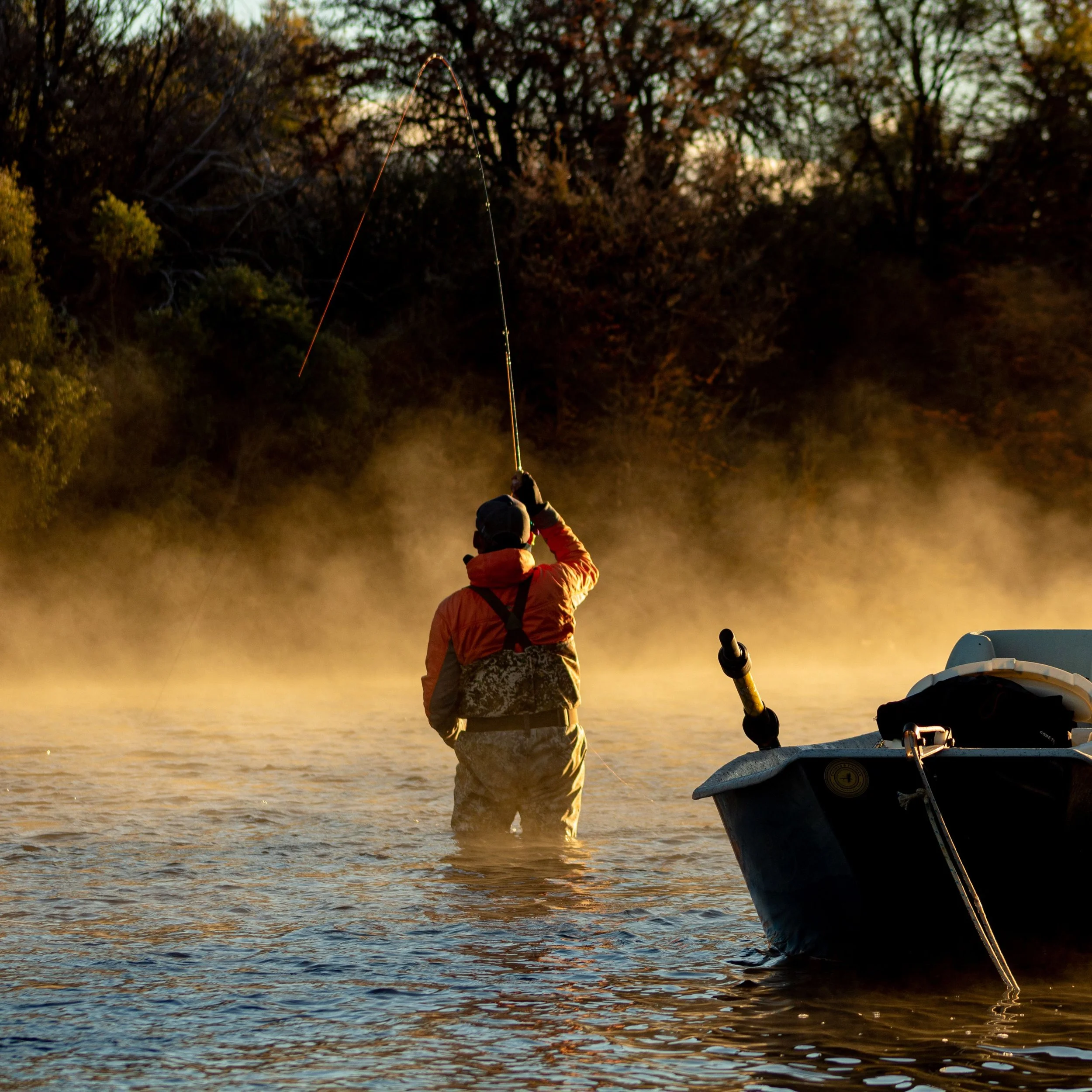 Person fishing from a boat at dusk