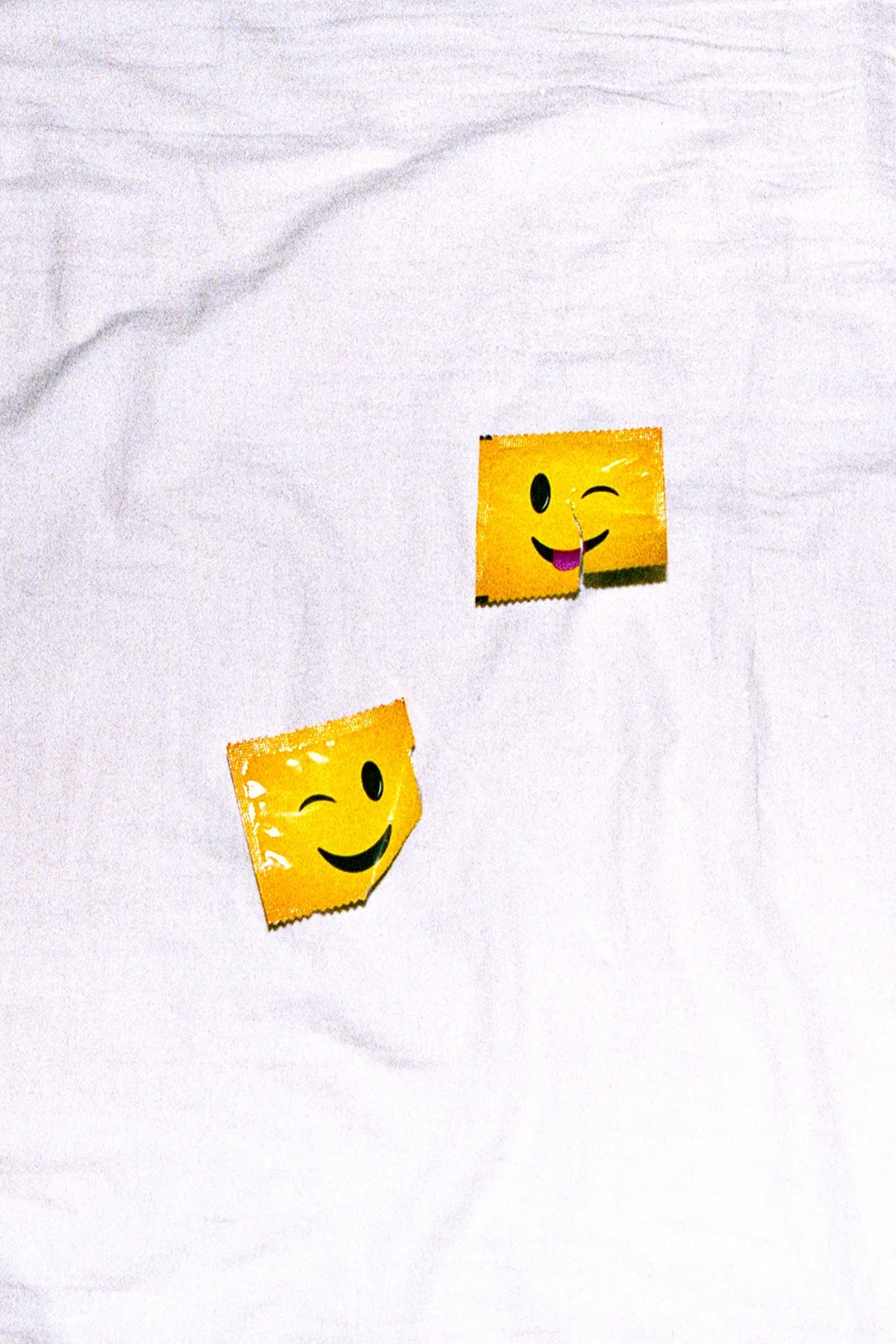 Two yellow smiley face stickers with winking eyes and big smiles on a white textured surface.
