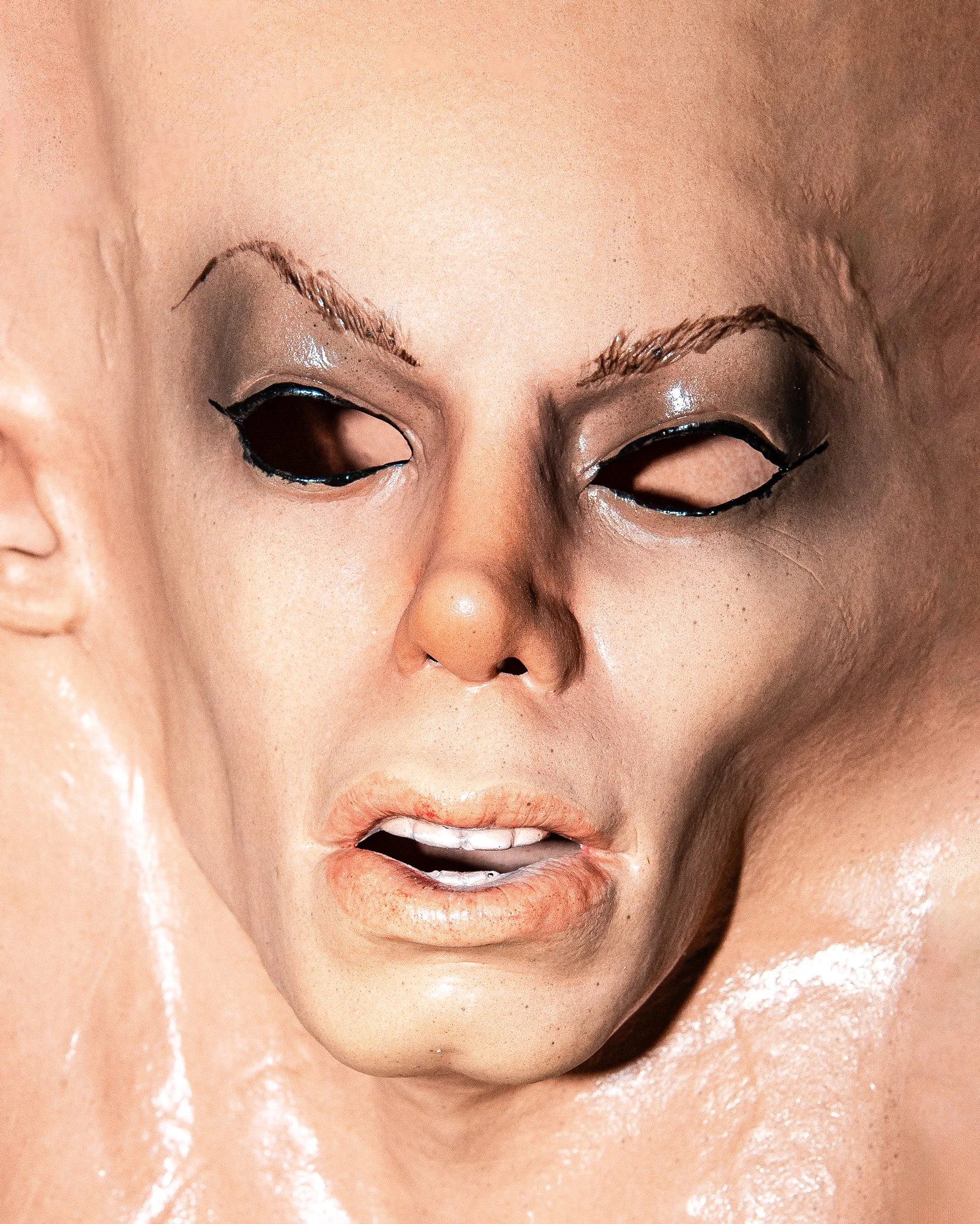 Close-up of a person's face with a focus on the mouth, eyes closed, and makeup. The skin appears to be wet or shiny.