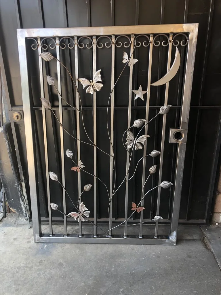 Decorative metal gate with butterflies, leaves, a crescent moon, and a star design.