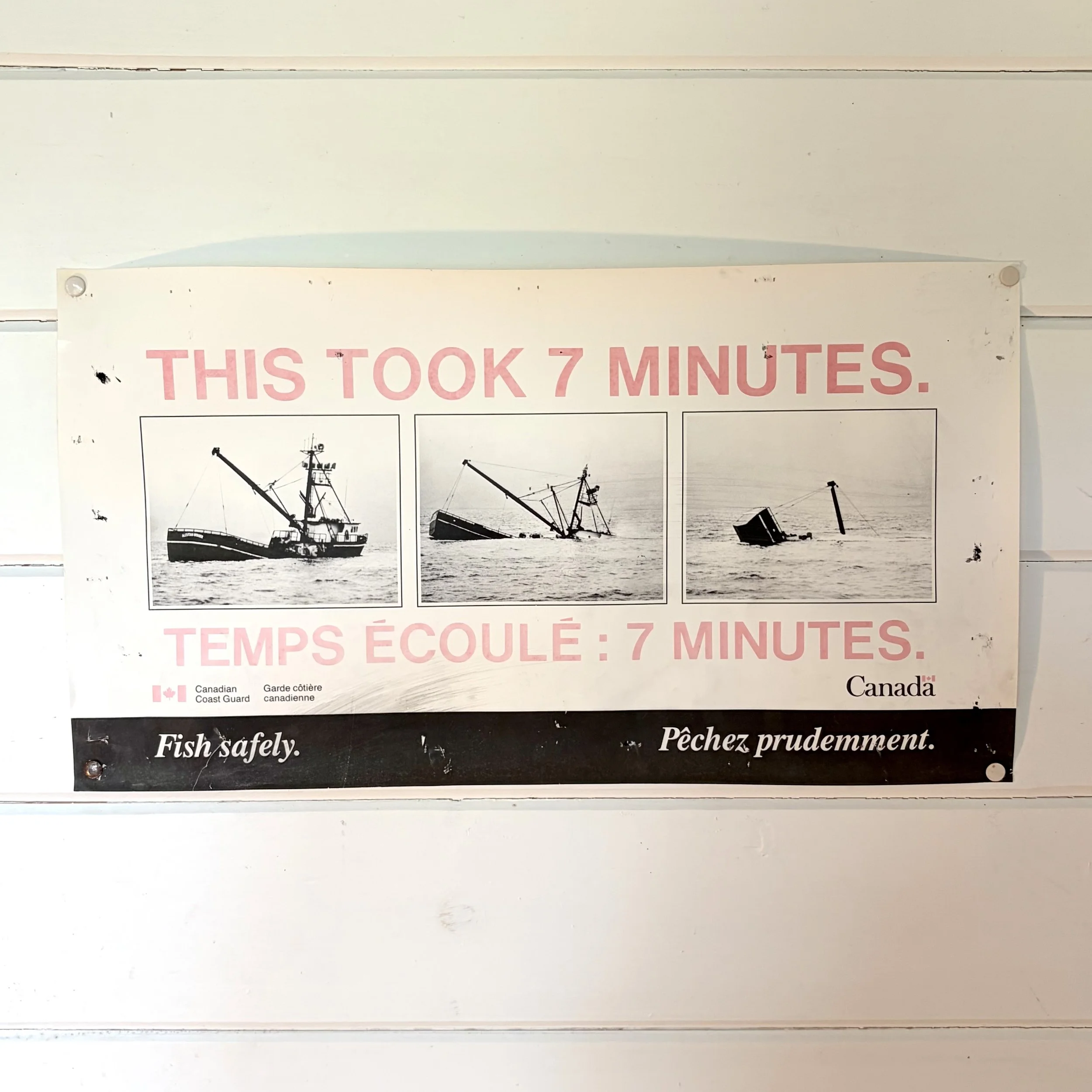 Sign with text in English and French stating it takes 7 minutes for the task, with black and white images of ships at sea underneath.
