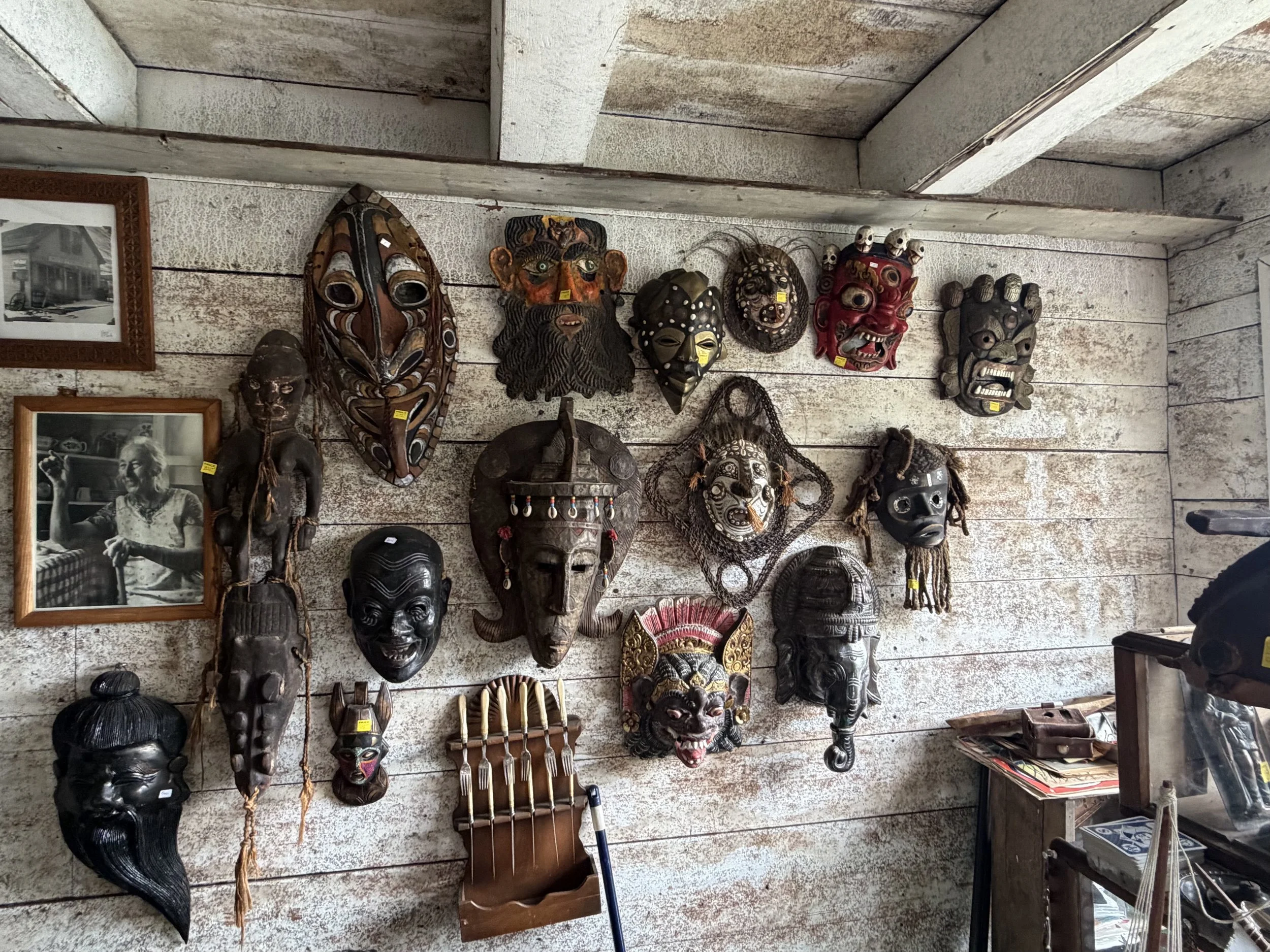 Display of masks and artifacts arranged on a rustic wooden wall.