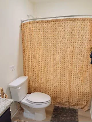 Bathroom with a toilet and beige patterned shower curtain
