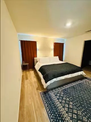 Hotel room with a bed, two dark curtains, a nightstand on each side, and a large dark wardrobe.