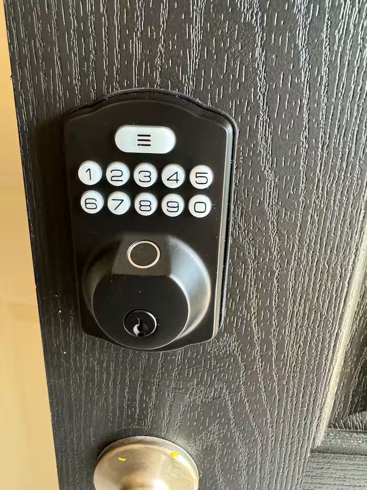 Digital keypad lock with circular handle and lock on a dark wood door.