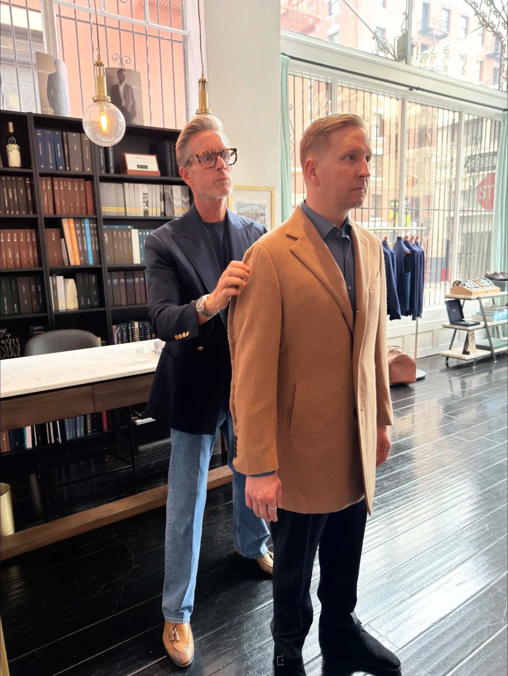 Christian Gardner pinning the sleeve of a client's custom camel coat during a fitting at the Scarborough showroom in San Francisco.