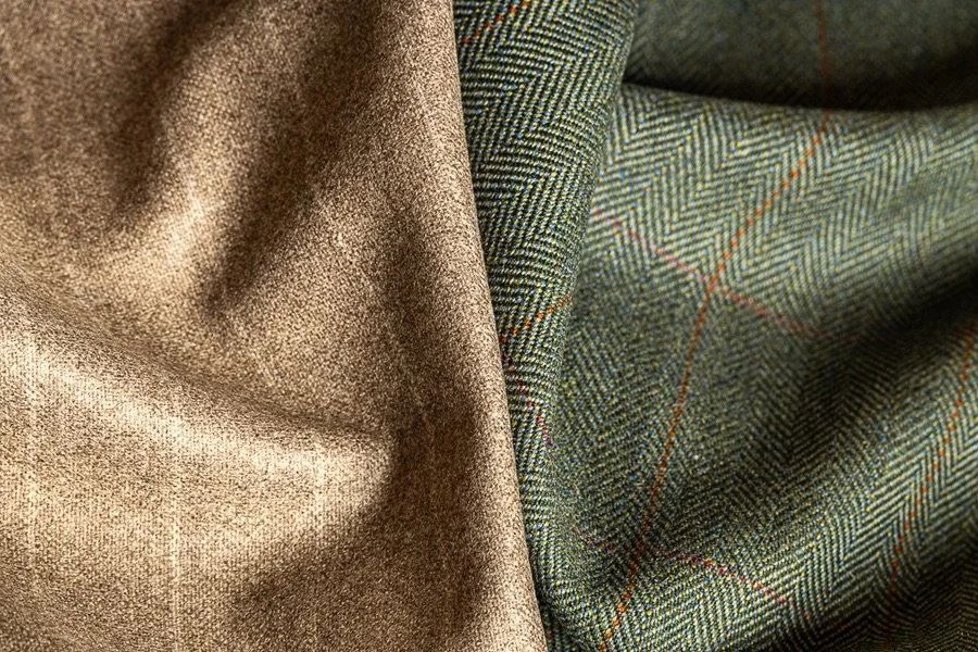 Close-up of two Loro Piana fabric pieces, one in solid beige and the other in green plaid with brown and cream lines.