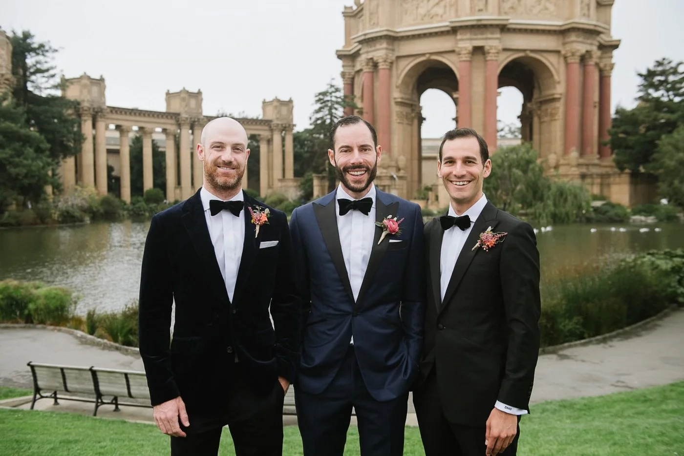 Three men in wearing Scarborough Custom Tailoring tuxedos standing outdoors in front of the Palace of Fine Arts in San Francisco, smiling at the camera.