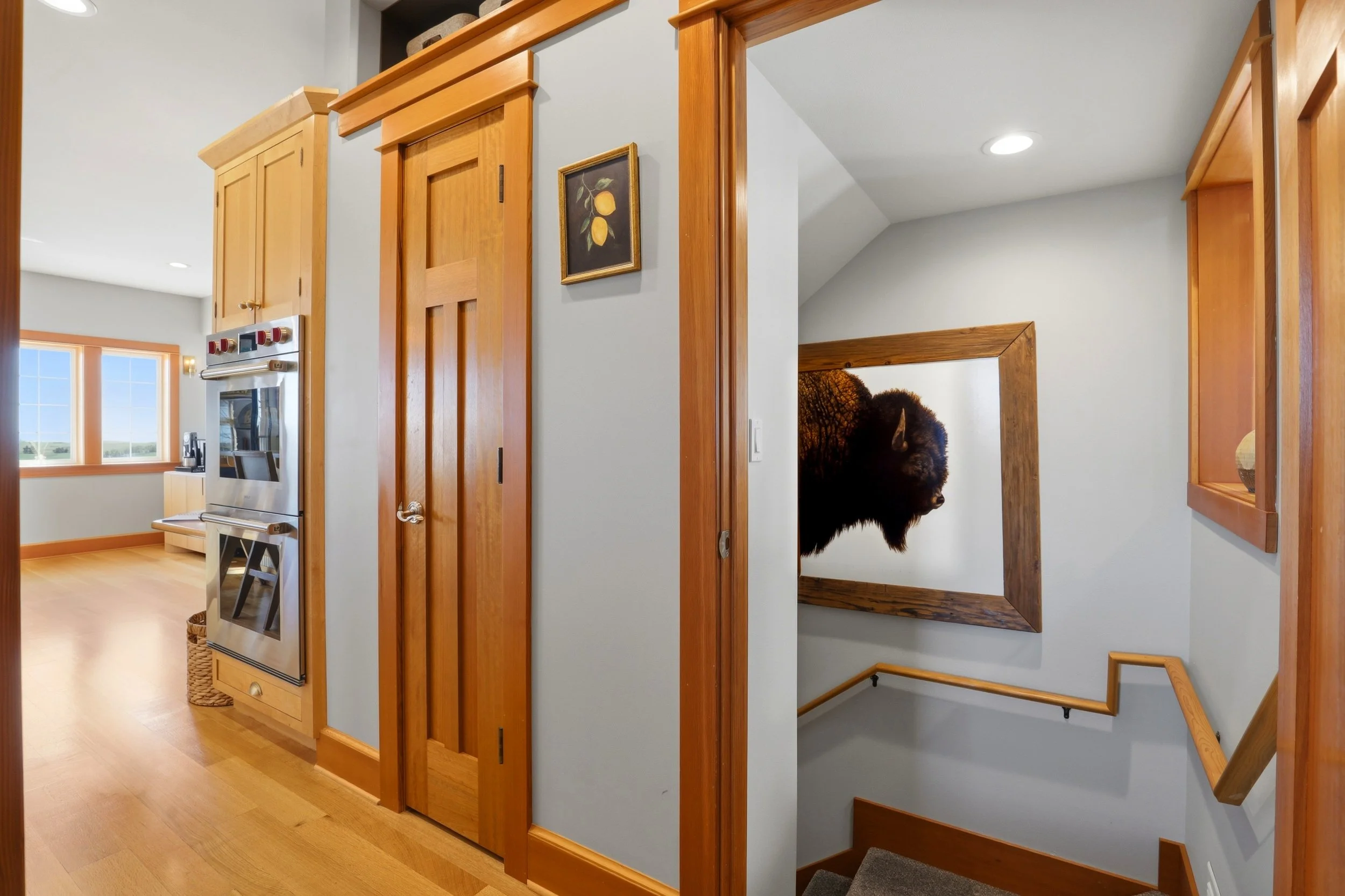 Hallway in a house with wooden doors, a framed picture of lemons on the wall, and a staircase with a bear rug visible at the top.