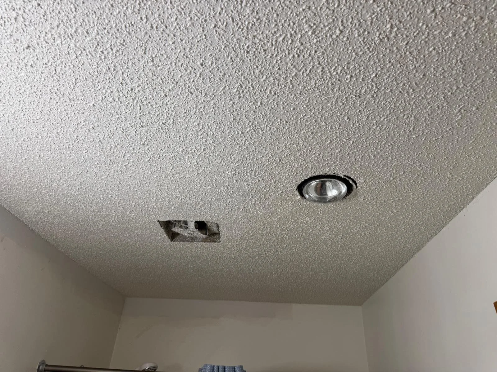 Ceiling with a missing vent cover and a recessed light fixture.