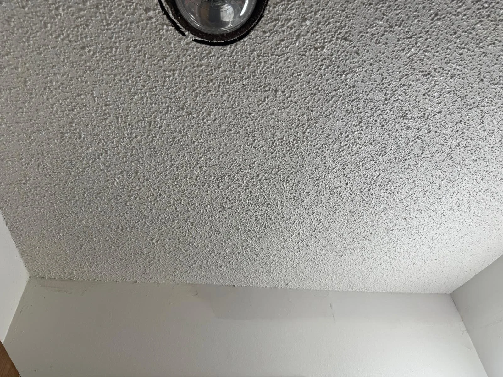 Ceiling with a textured popcorn finish and a smoke detector installed.
